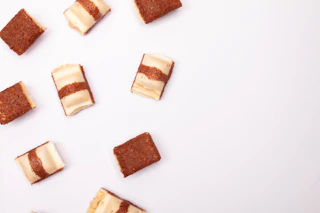 Several chocolate and cream candy pieces scattered on white.