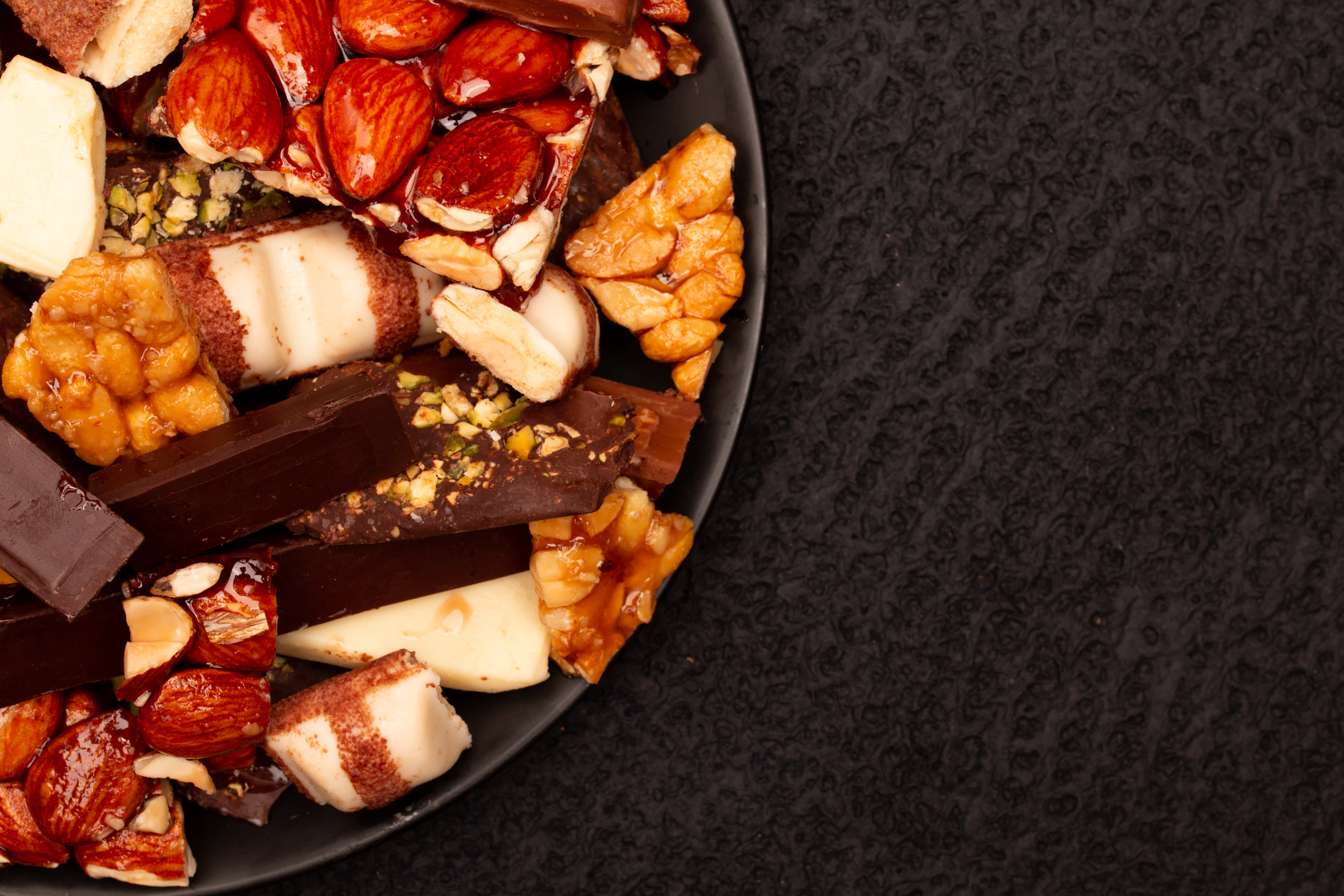 Surtido de chocolates y frutos secos tostados sobre una superficie oscura
