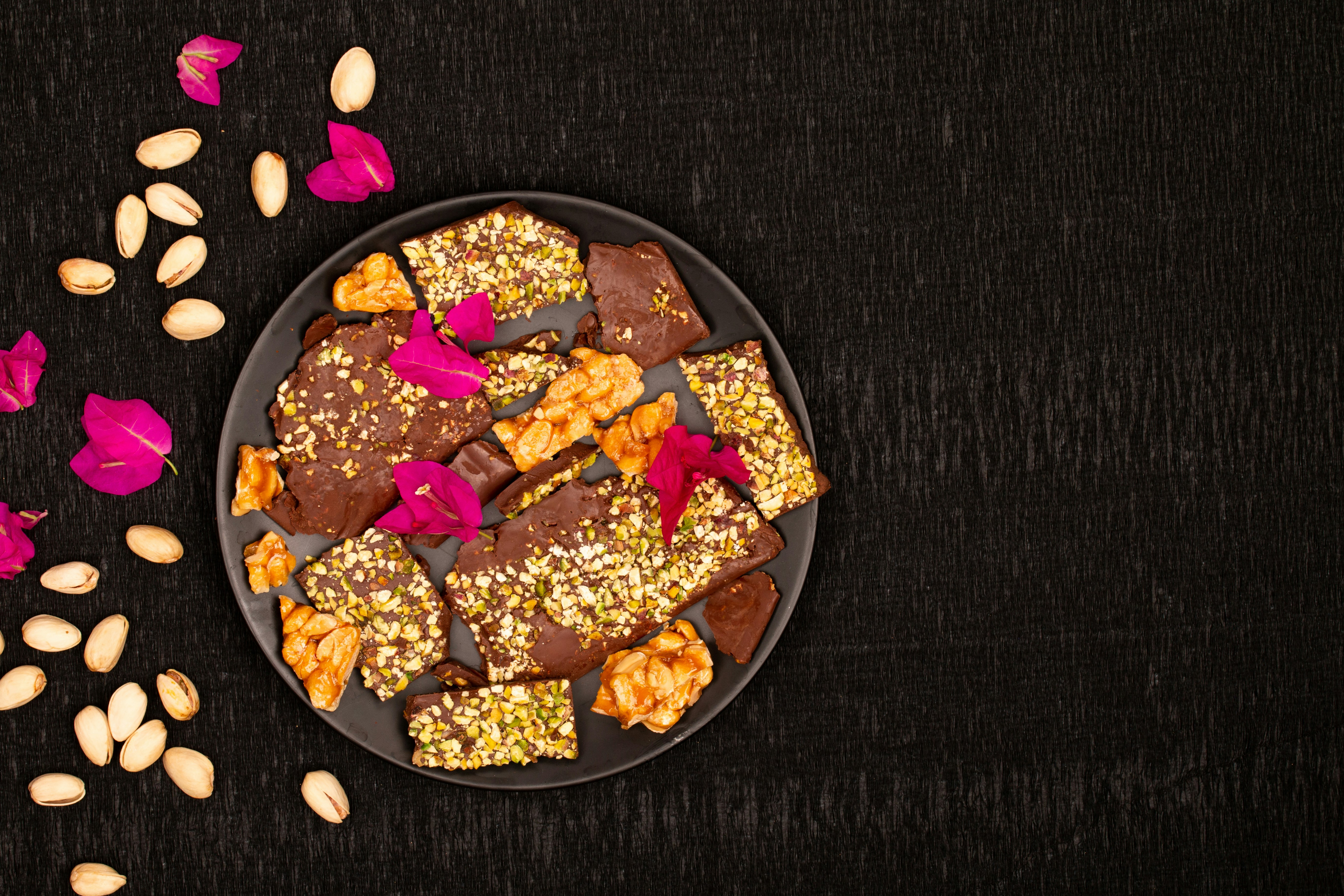 Schoko-Rinde mit Pistazien und rosa Blumen auf dem Teller