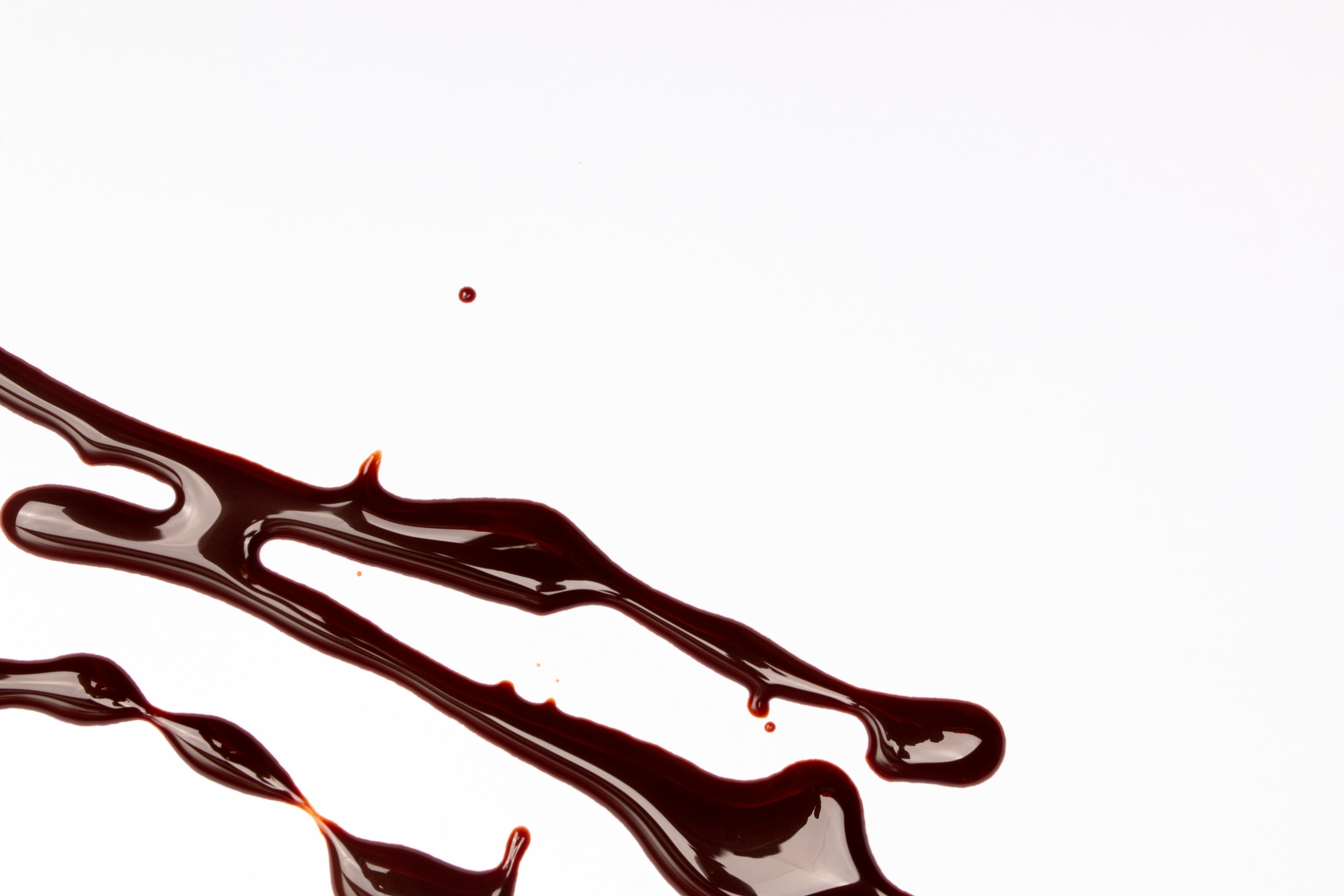 Dark chocolate syrup drizzled on a white surface.