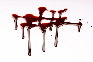 Dark chocolate syrup dripping on a white surface