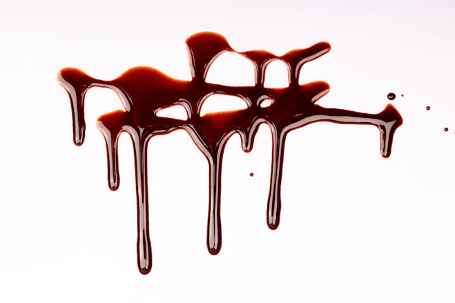 Dark chocolate syrup dripping on a white surface