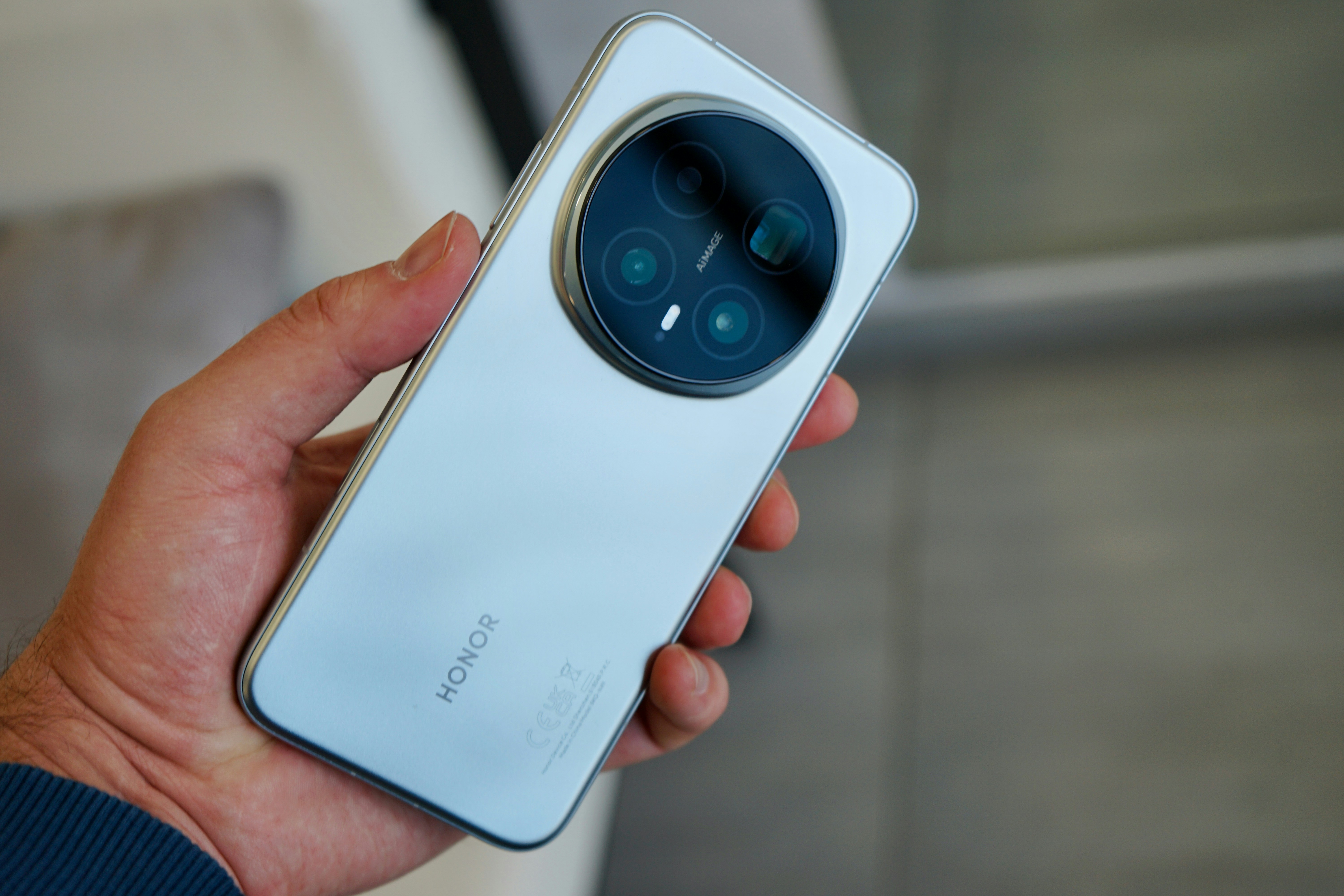 Segurando um smartphone prateado com um módulo de câmera circular.