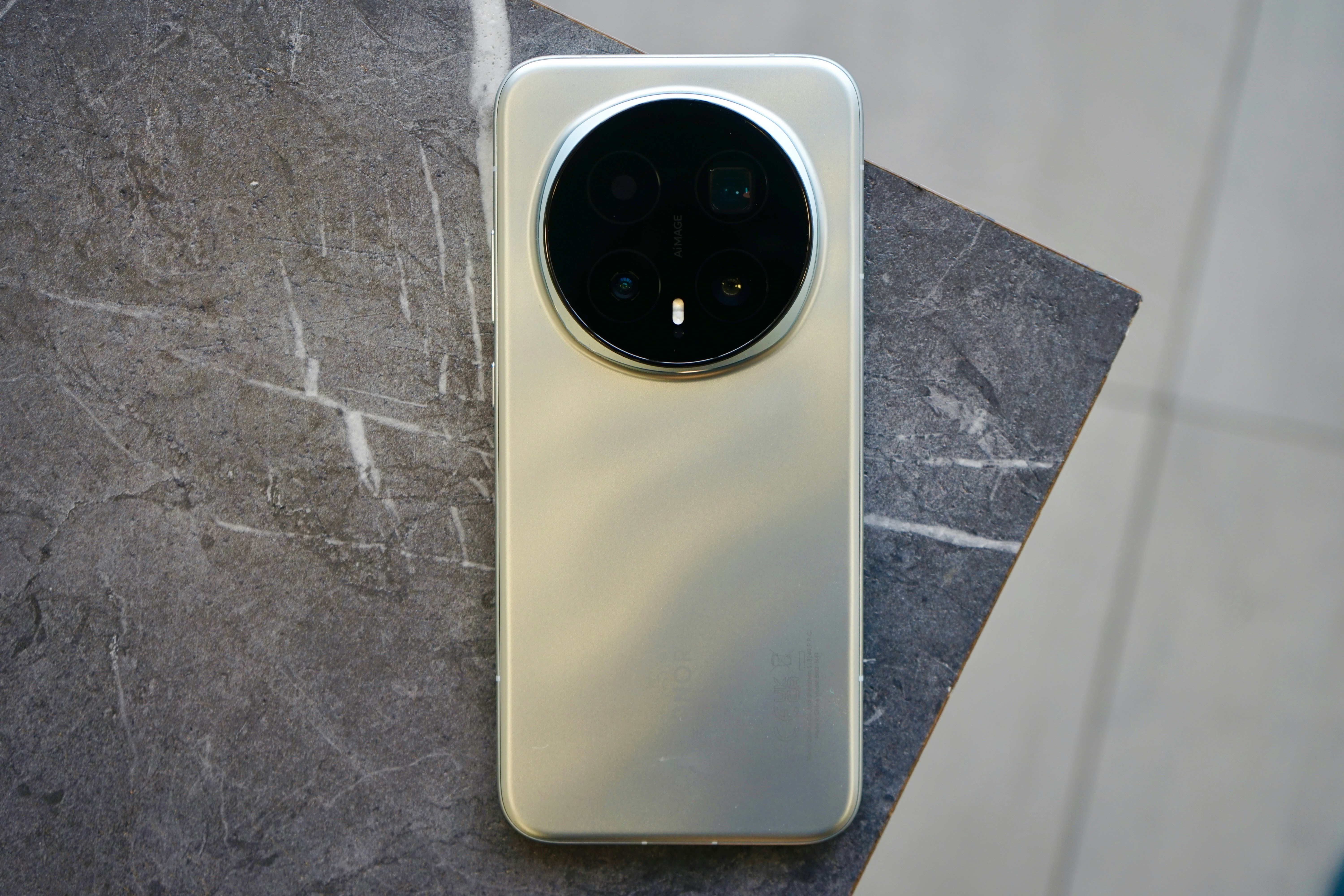 Smartphone dourado com grande câmera circular sobre superfície marmorizada