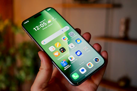 Hand holding a smartphone with a green home screen.