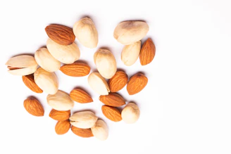 A pile of almonds and pistachios on a white background.
