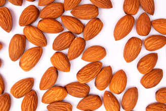 A pile of raw almonds scattered on a white surface.
