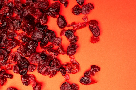 Dried cranberries scattered on an orange background