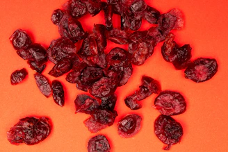 A pile of dried cranberries on an orange background
