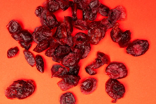 A pile of dried cranberries on an orange background
