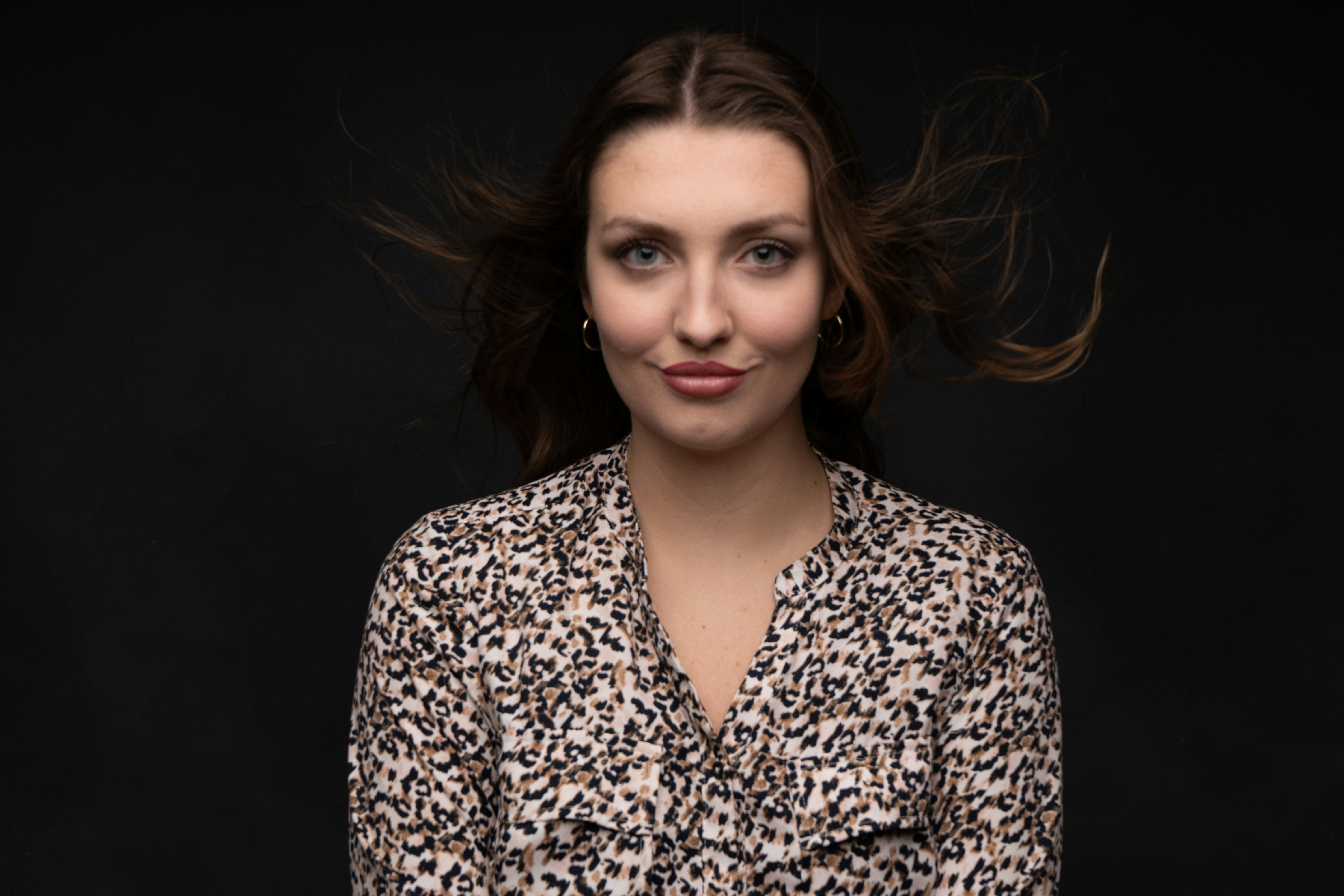 Woman with windblown hair against a dark background