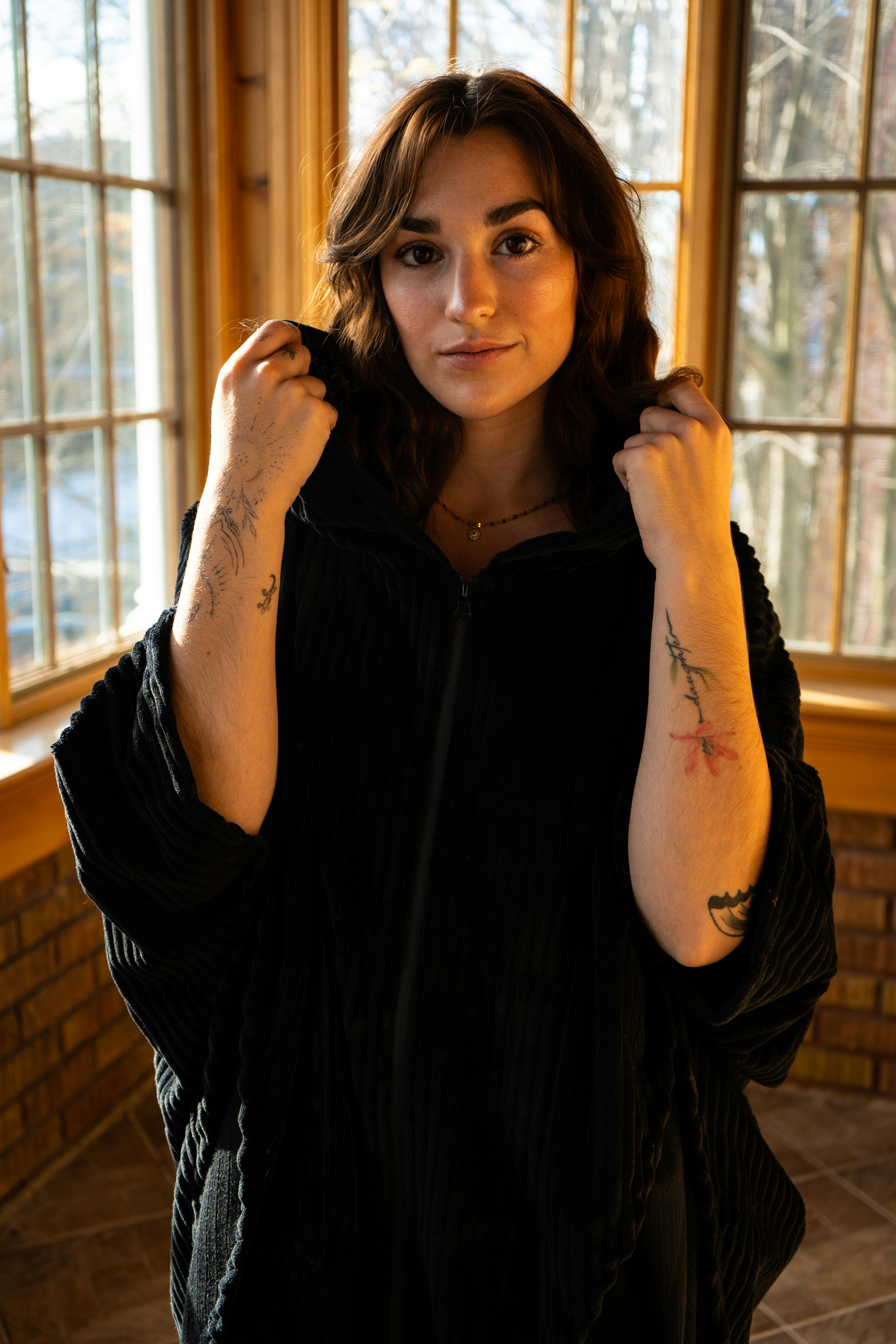 A woman wearing a dark hooded robe indoors