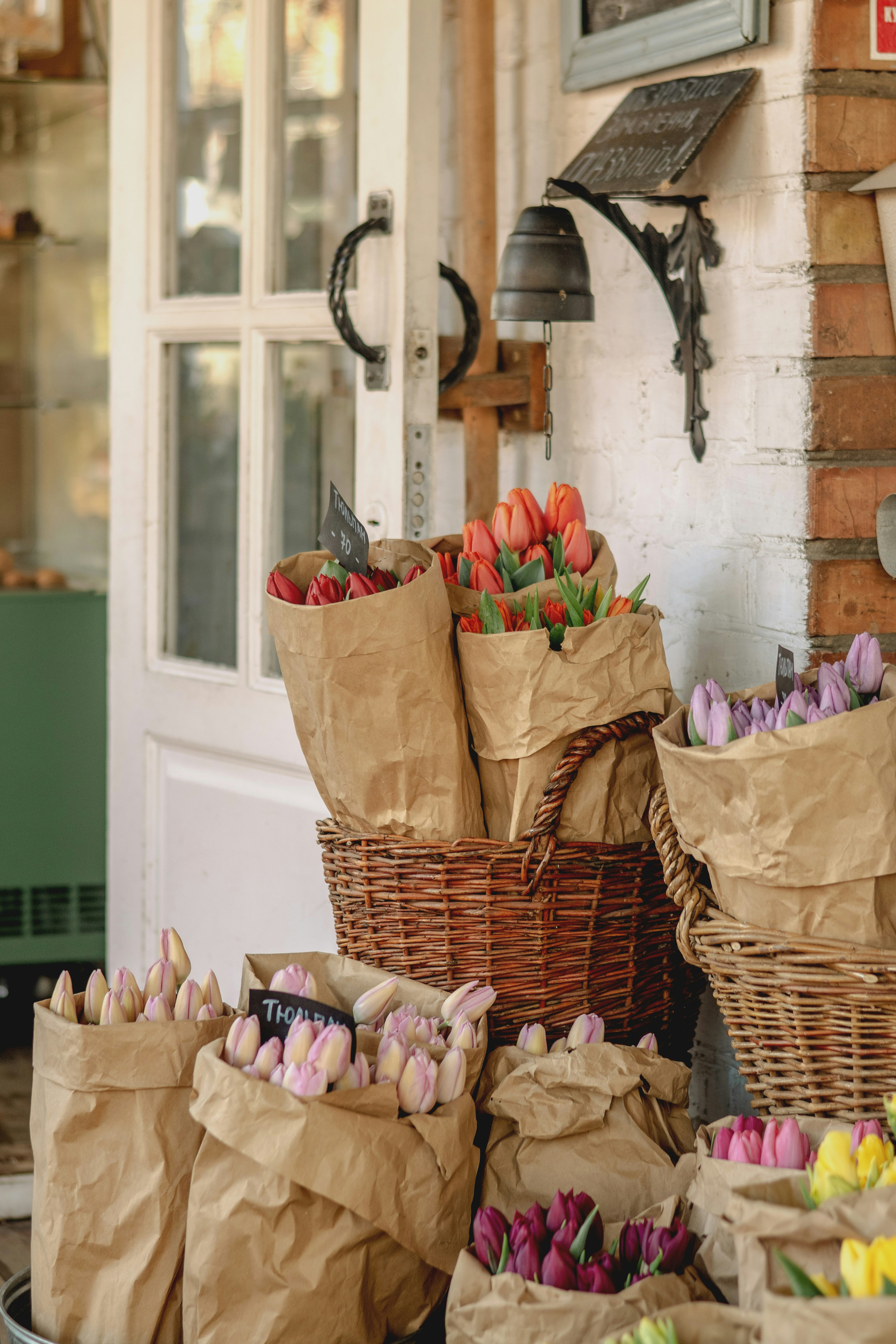 Ramos de tulipanes en papel y cestas fuera de la tienda expuestas.