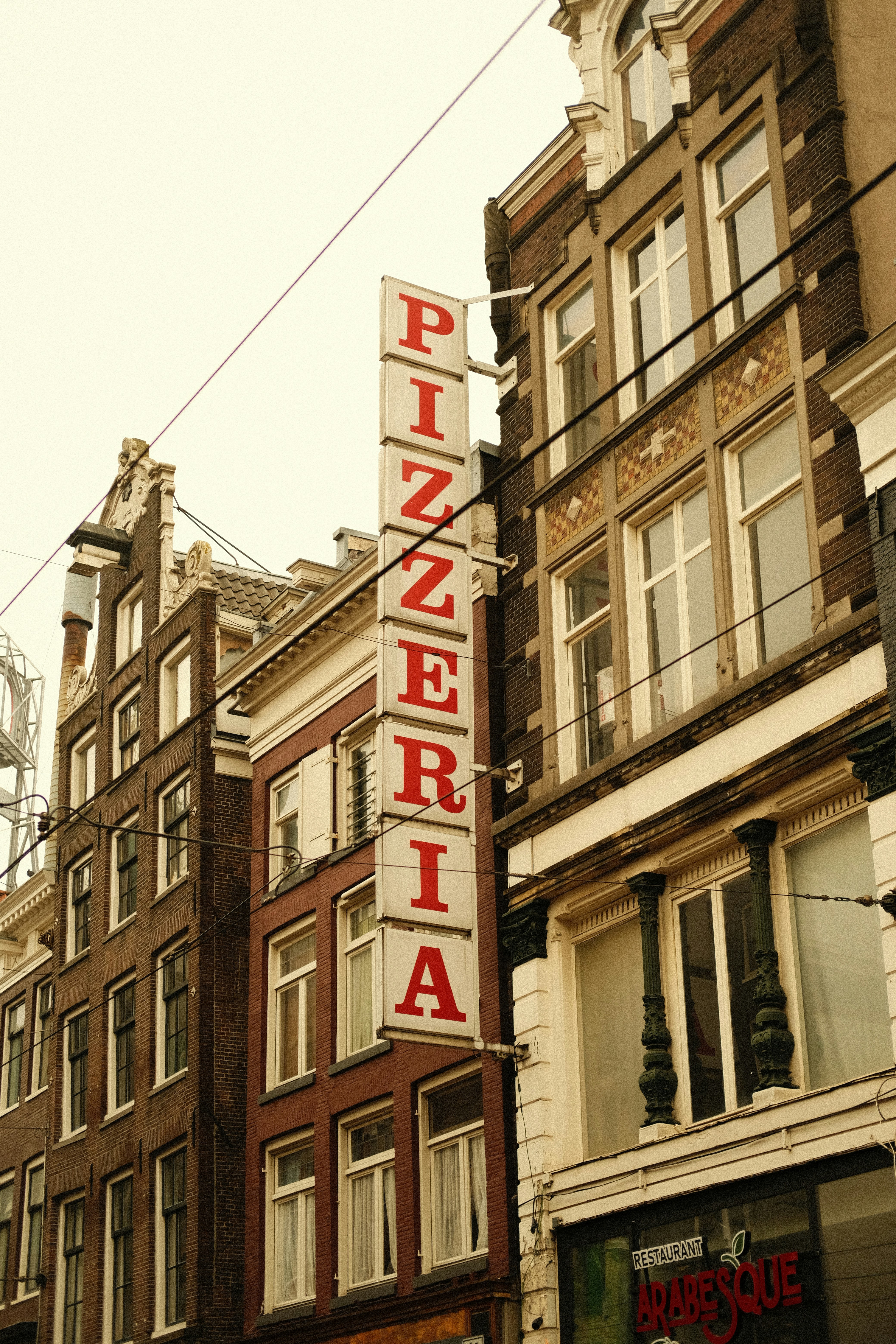 Vertikales Pizzeria-Schild an einer Gebäudefassade.