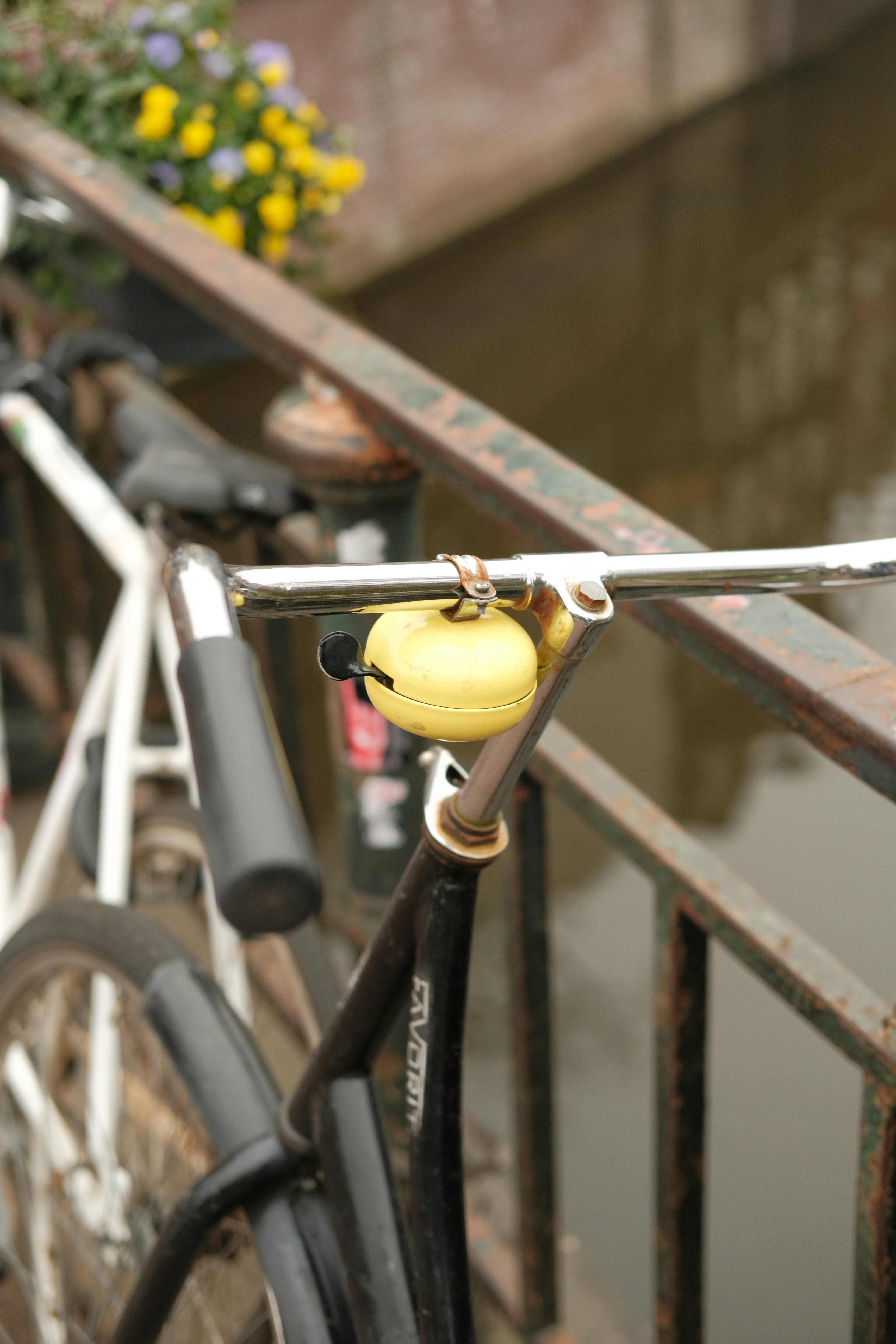 Gelbe Fahrradklingel, die am Lenker in der Nähe eines Kanals befestigt ist.