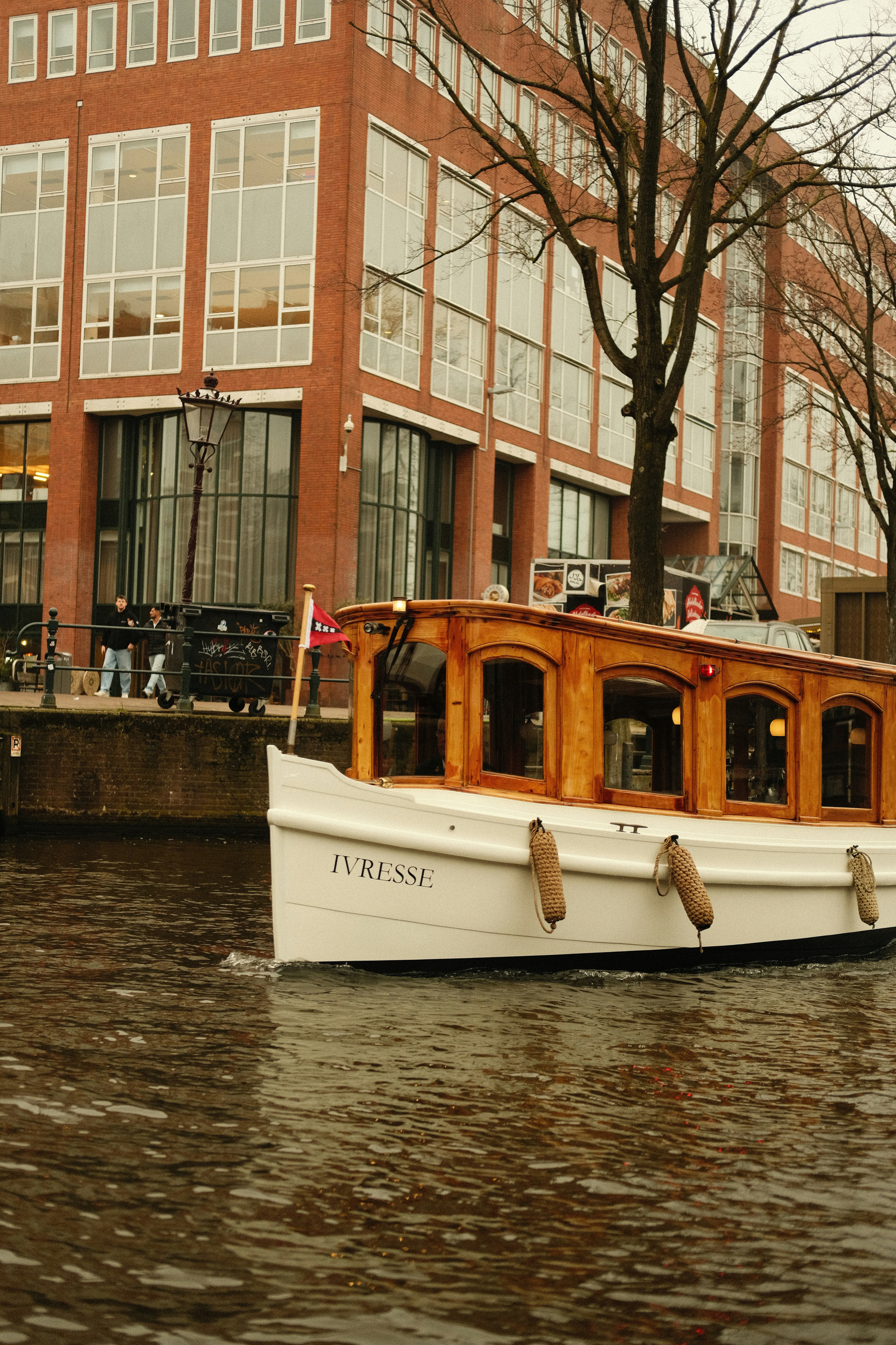 Ein weißes Boot mit Holzakzenten segelt auf einem Kanal.