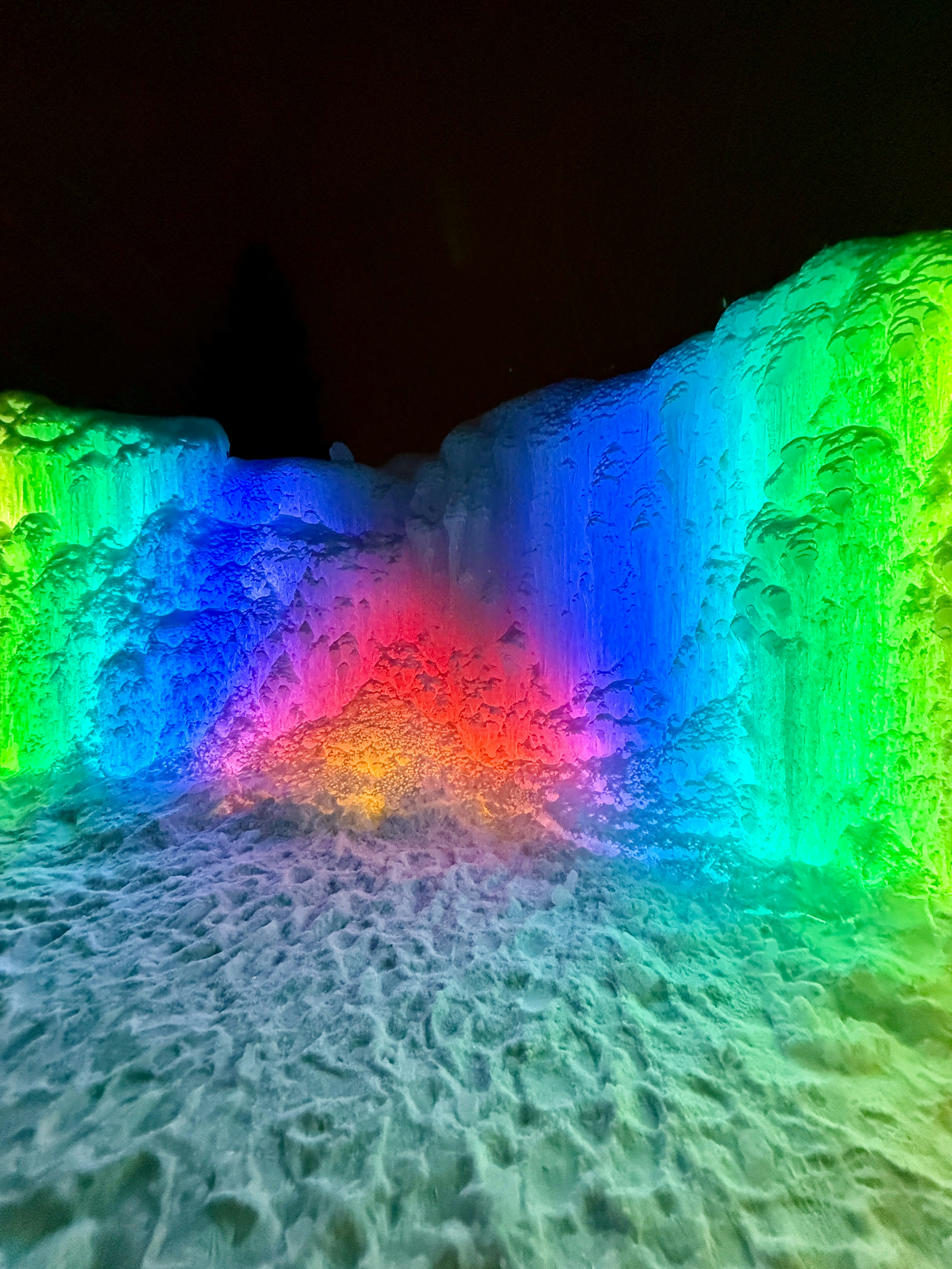 Ice formation lit with vibrant rainbow colors at night