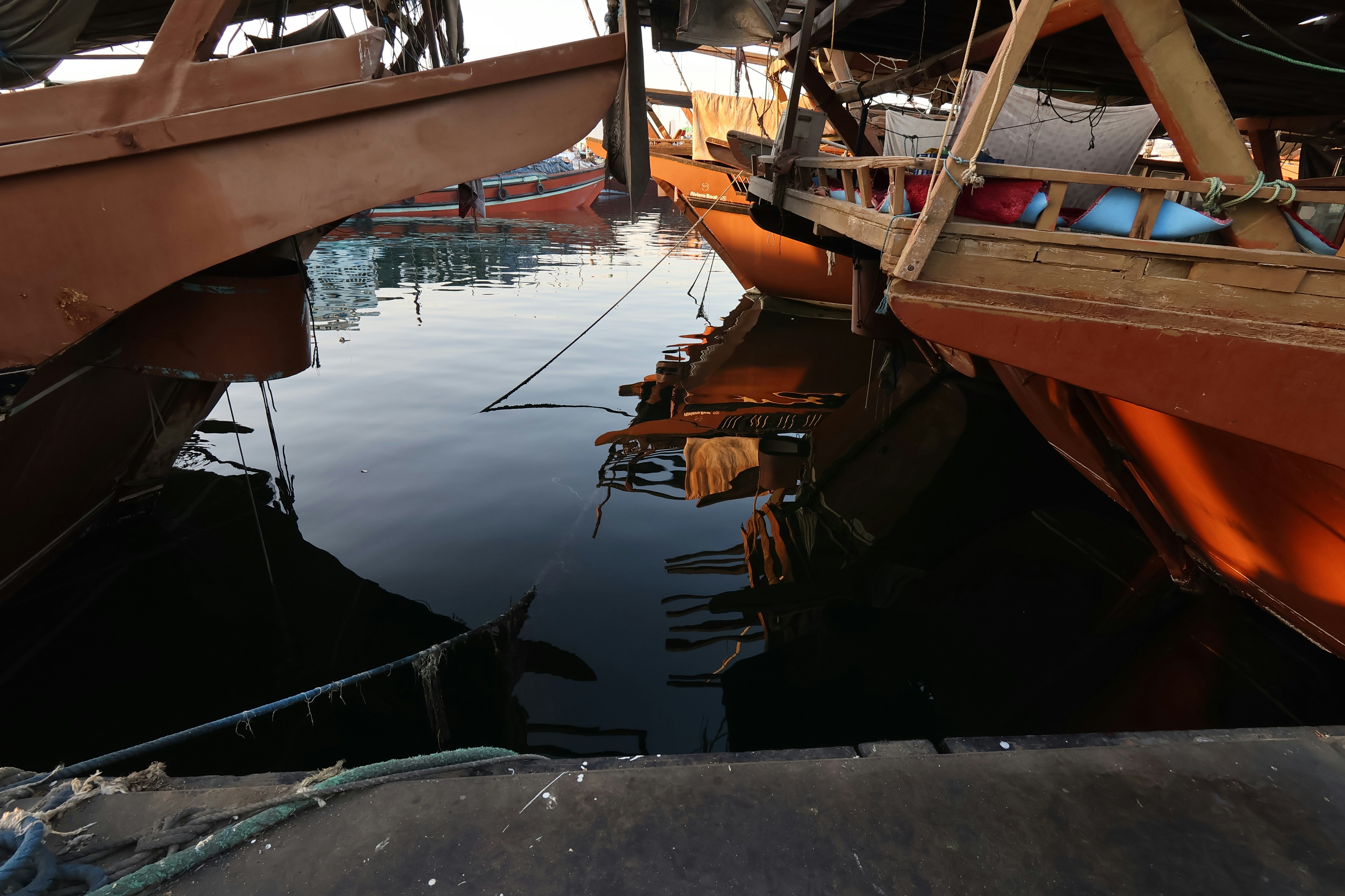 Fishing boats docked in a calm harbor at dawn.