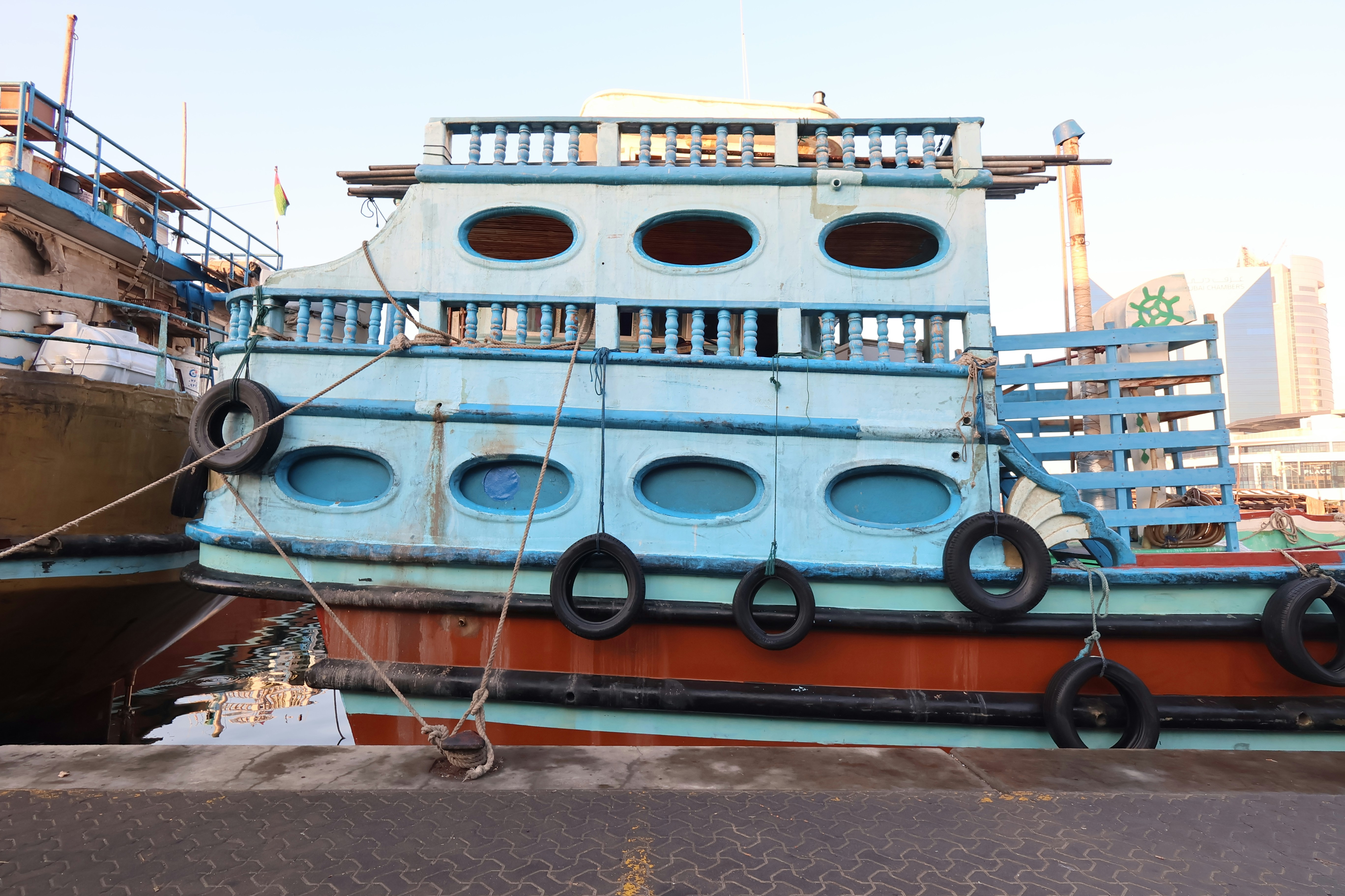 A blue and orange boat docked by the water