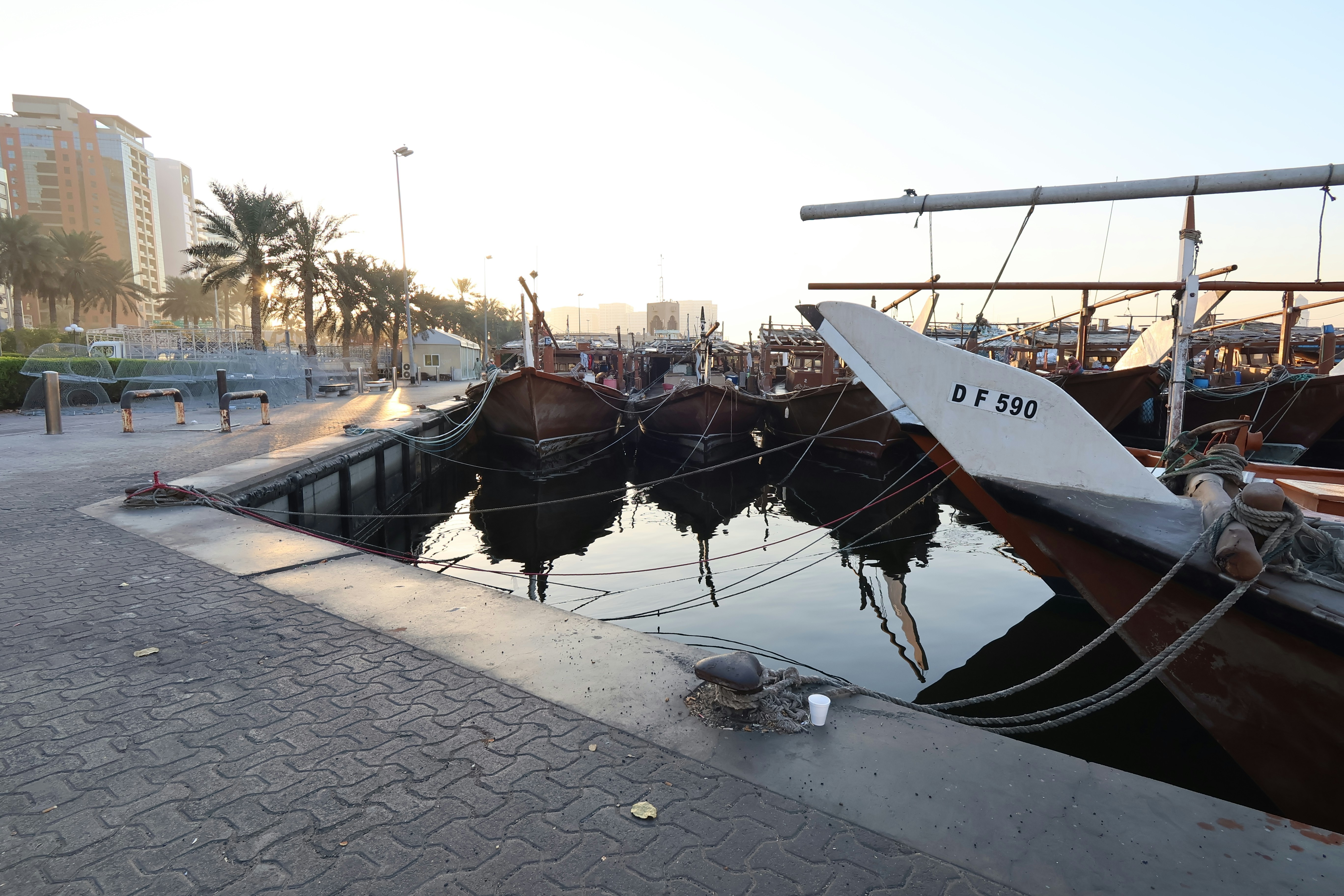Dhow boats docked in a harbor at sunrise