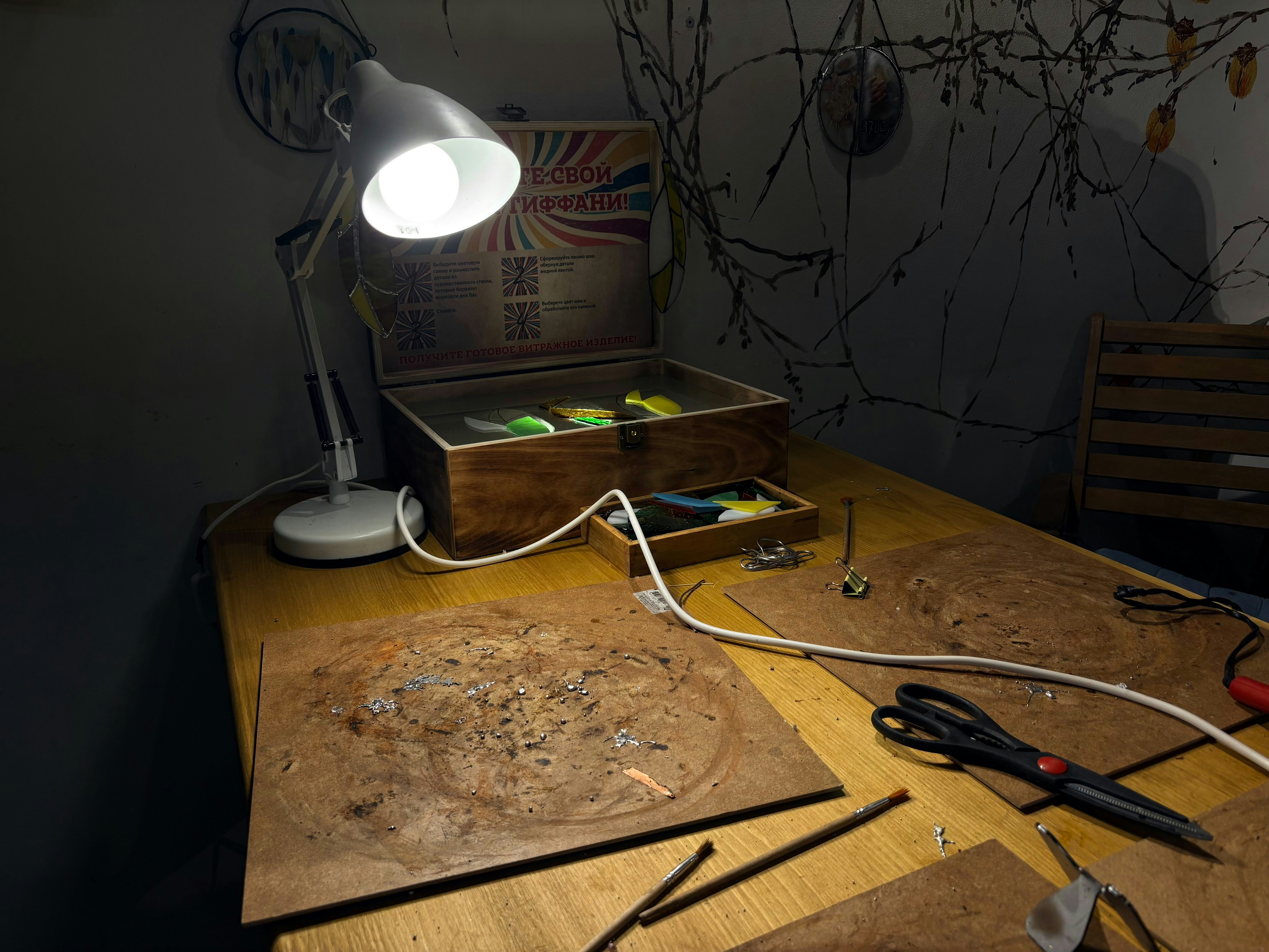 Desk with a lamp illuminating a wooden box of lures.