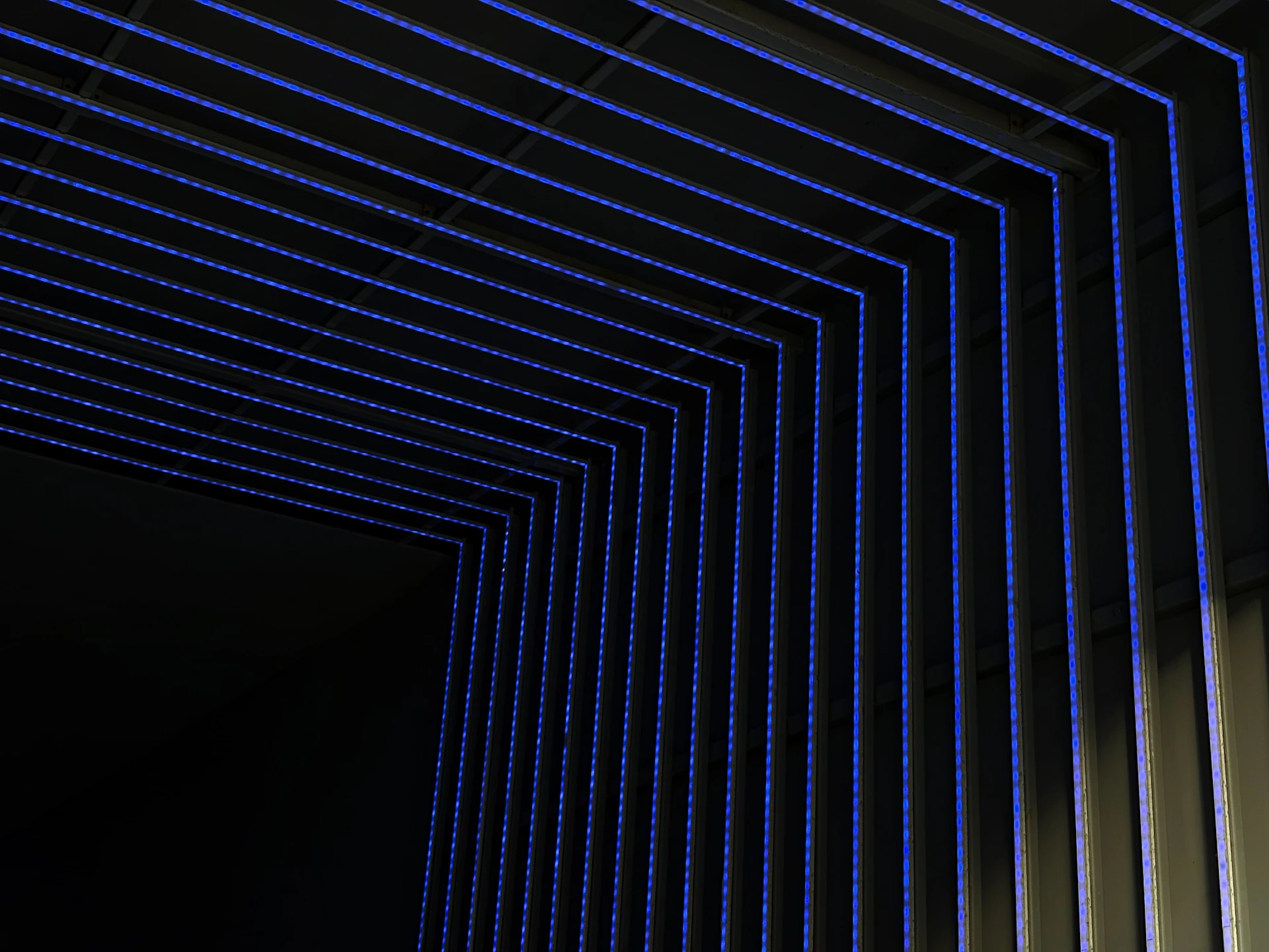 Blue neon lights form geometric patterns in darkness