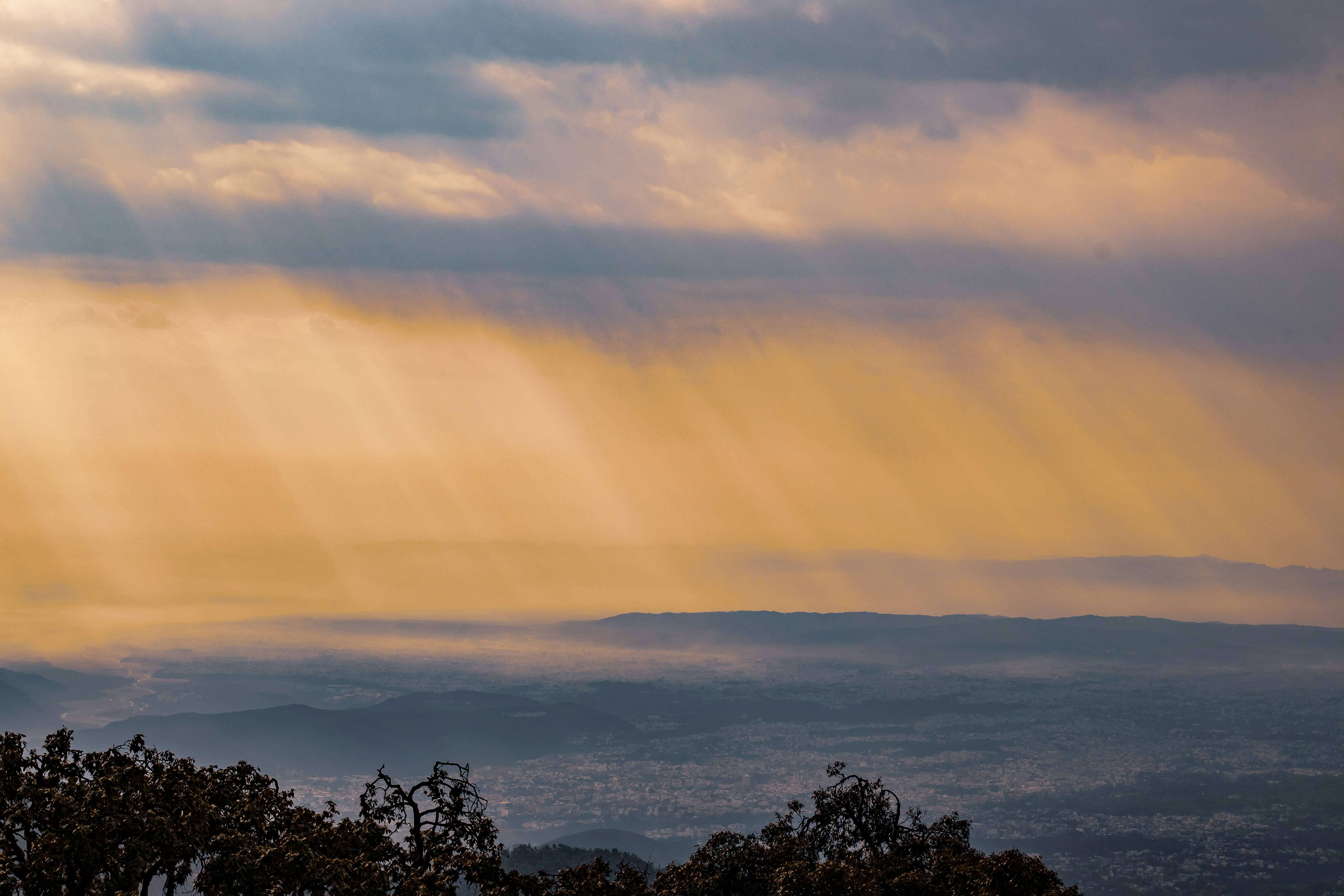 Los rayos de sol atraviesan nubes dramáticas sobre colinas lejanas