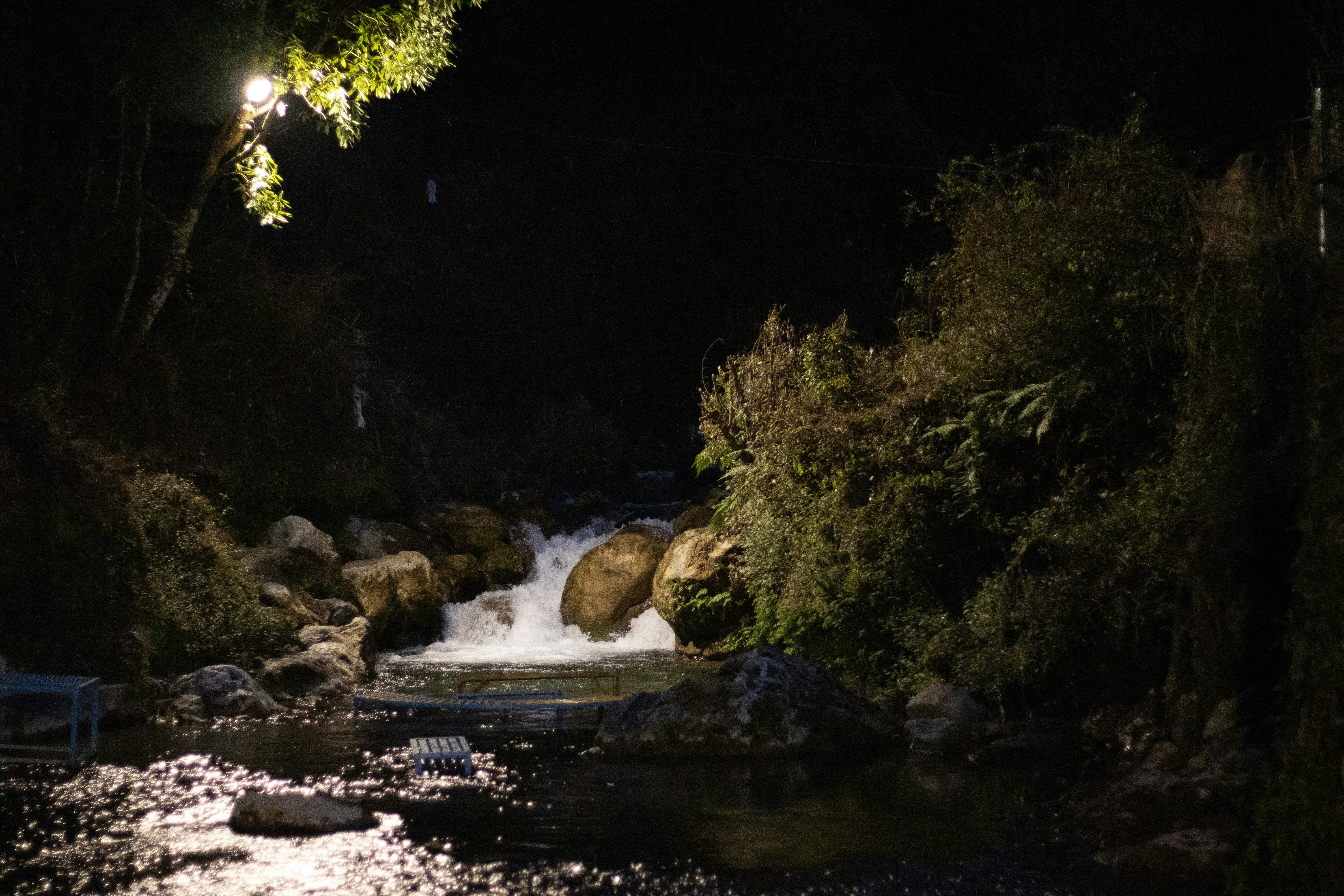 Un arroyo rocoso fluye de noche bajo luz artificial.