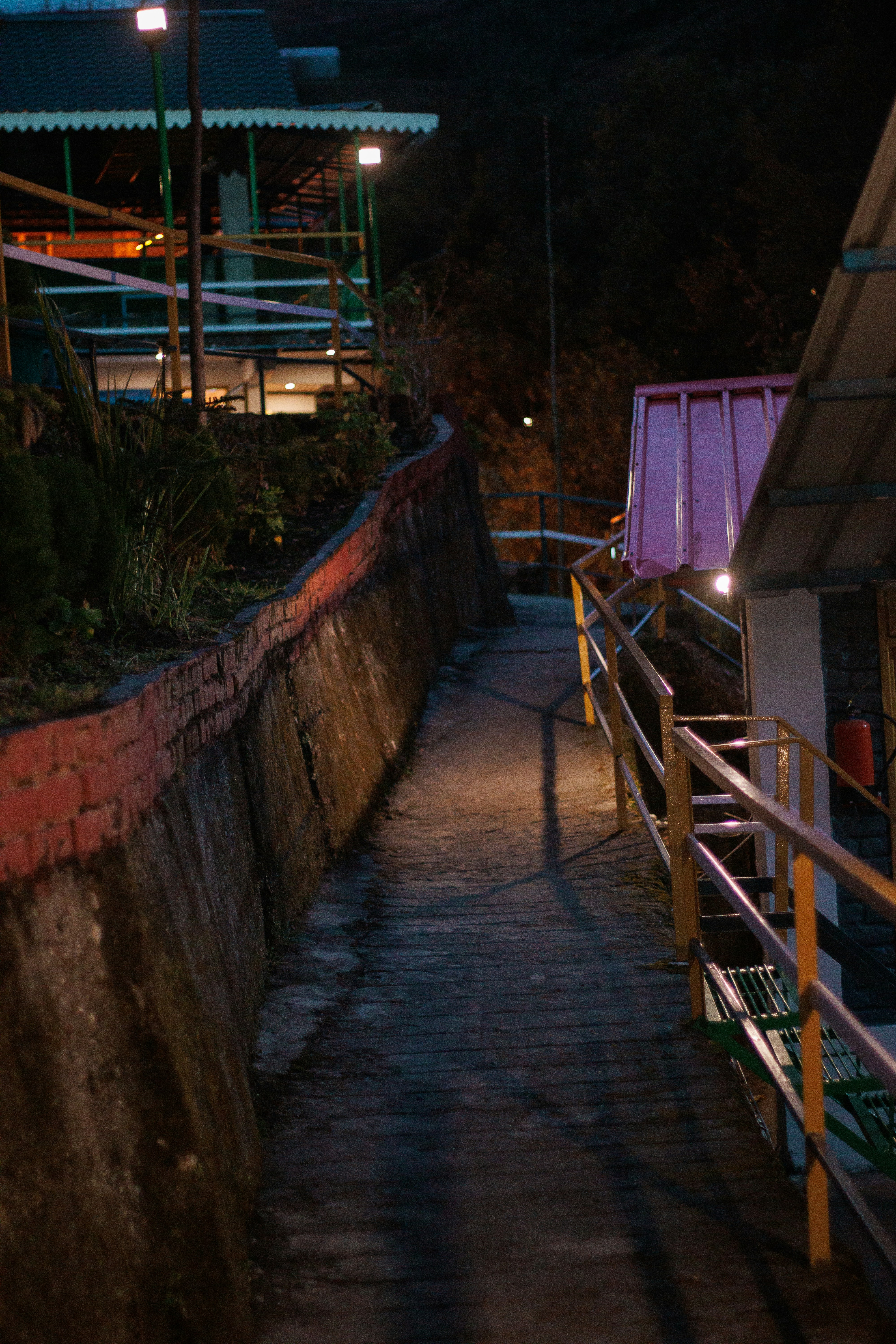Un camino tenuemente iluminado con barandillas por la noche.