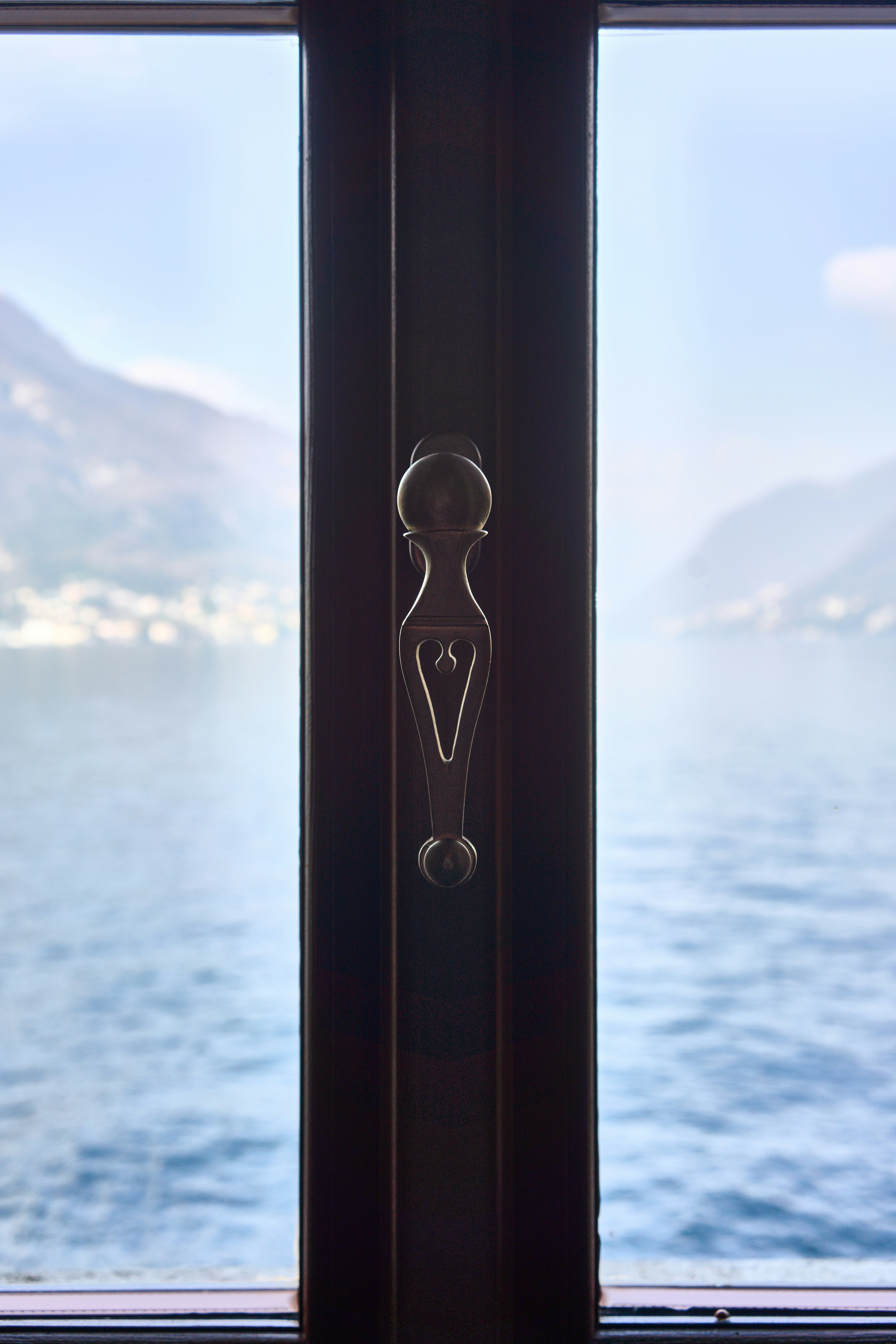 Vista dell'acqua calma e delle colline lontane attraverso la finestra