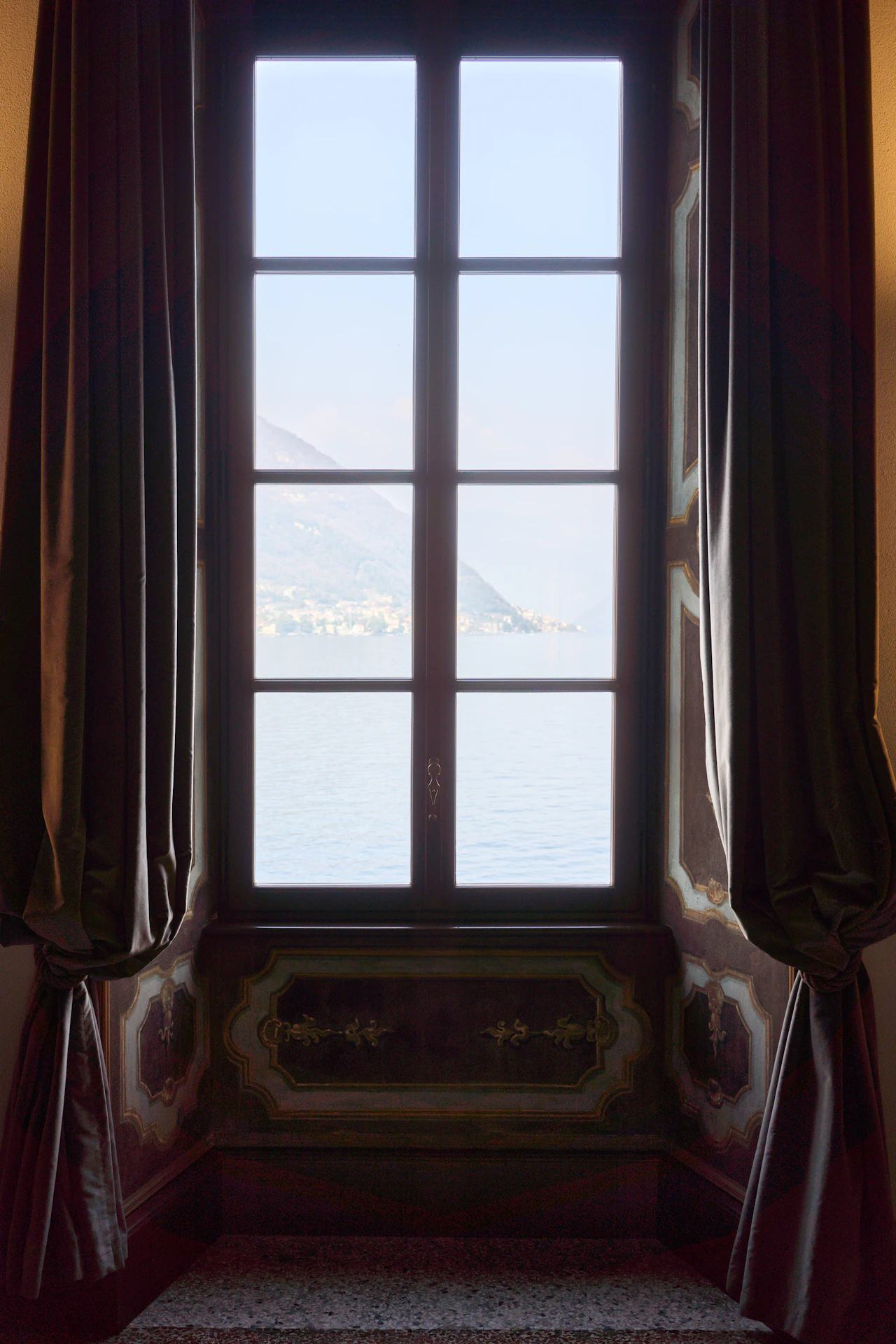 Lake and mountains framed by the window of a villa drawing room
