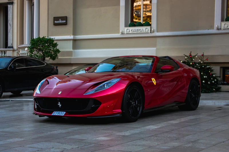 A shiny red Ferrari parked outside a prestigious building.