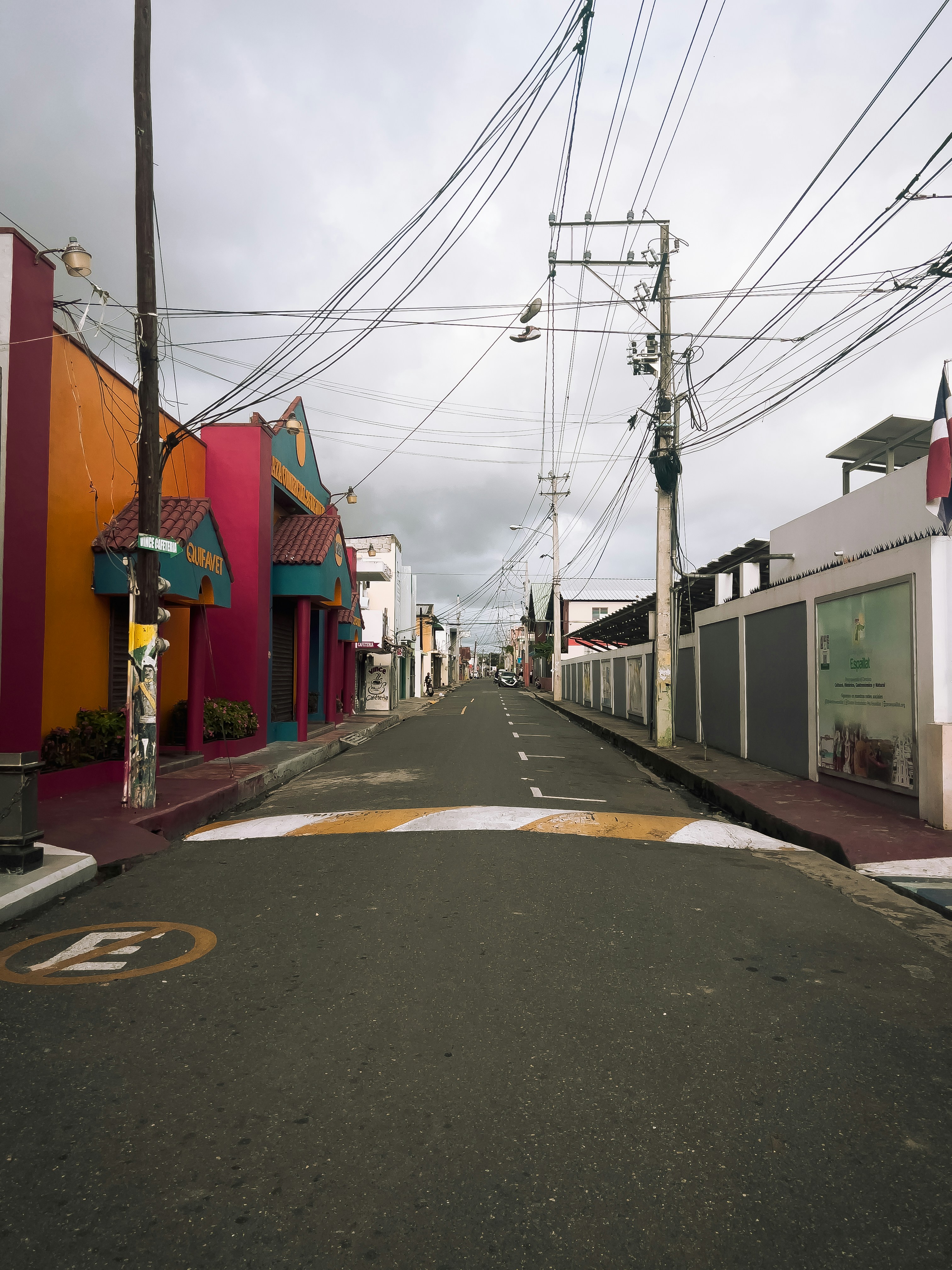 Prédios coloridos alinham uma rua com fios aéreos.