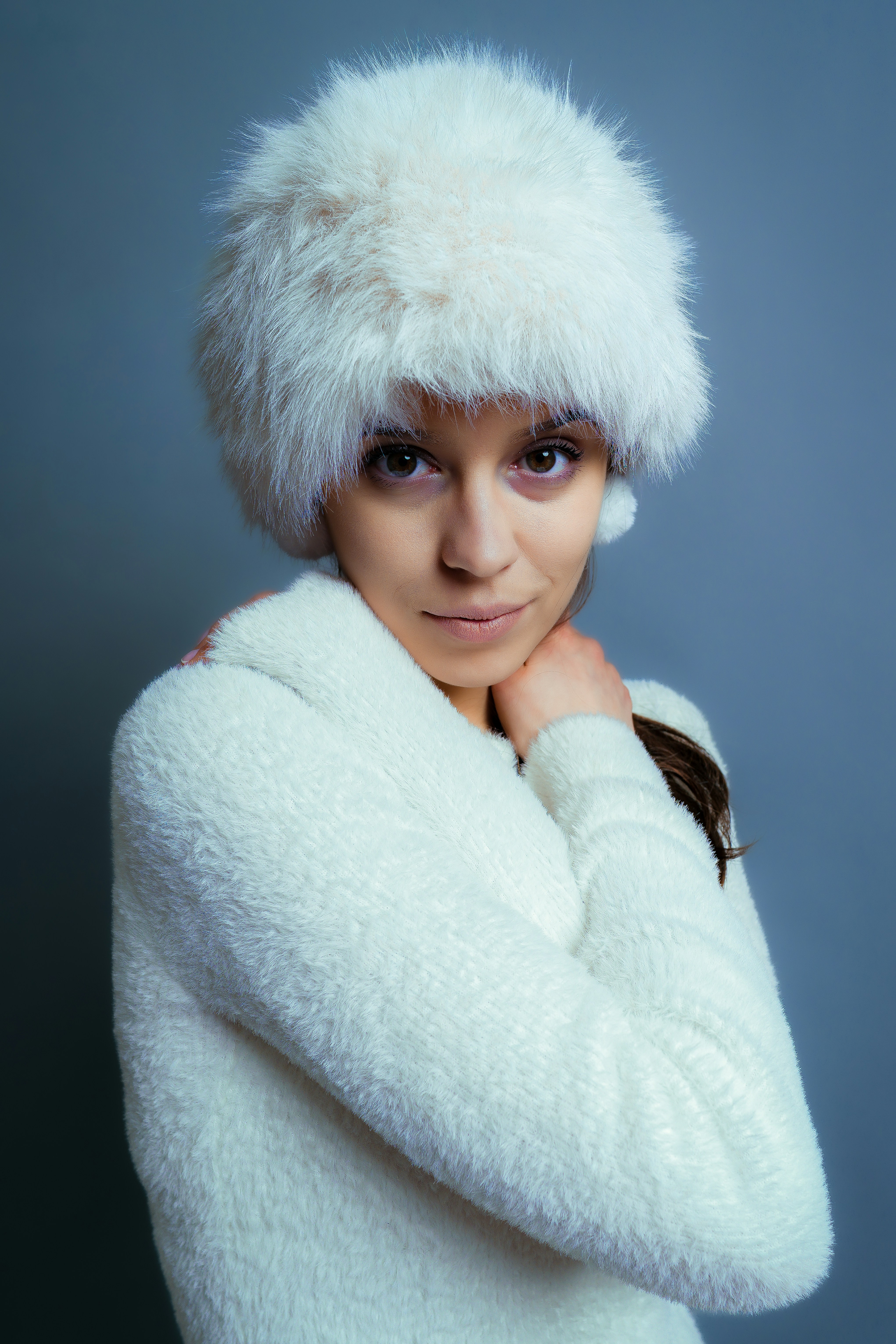 Femme portant un chapeau blanc duveteux et un pull.