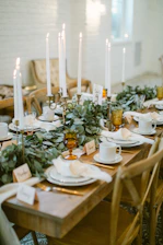 A beautifully set dining table with candles and greenery.