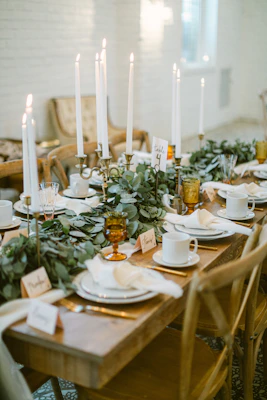 A beautifully set dining table with candles and greenery.