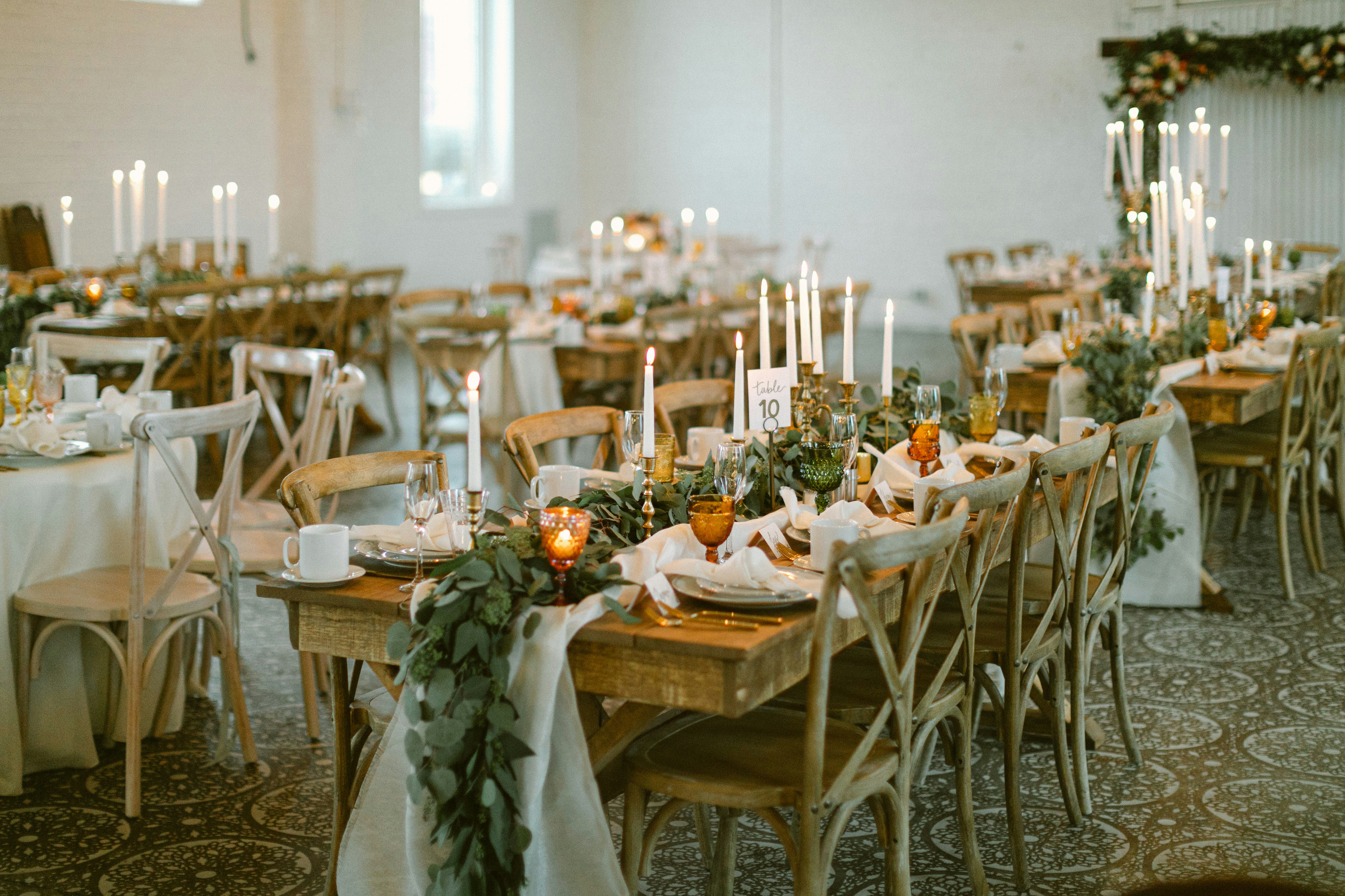Tables de réception de mariage dressées avec des bougies et de la verdure