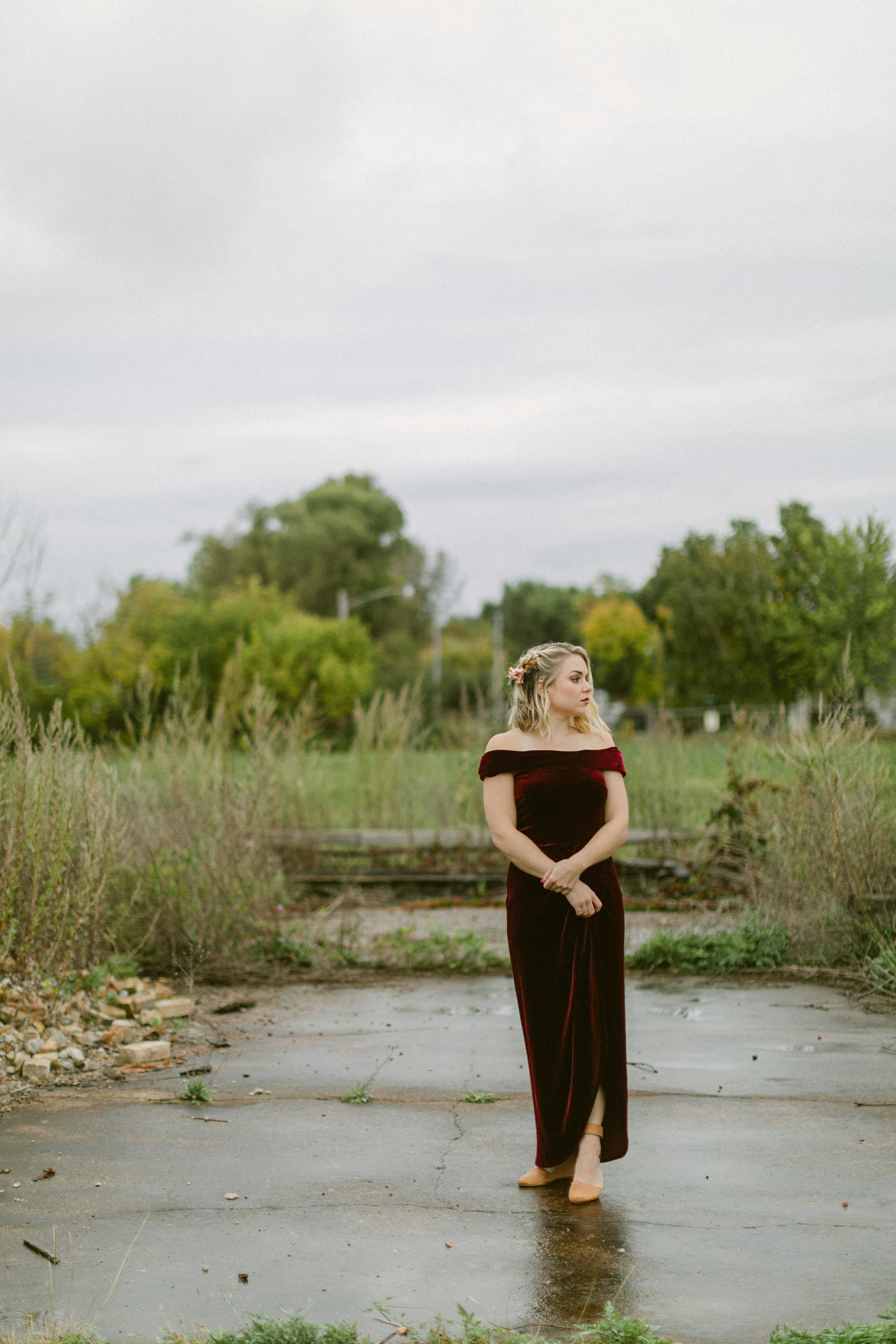 Femme en robe bordeaux se tient dehors