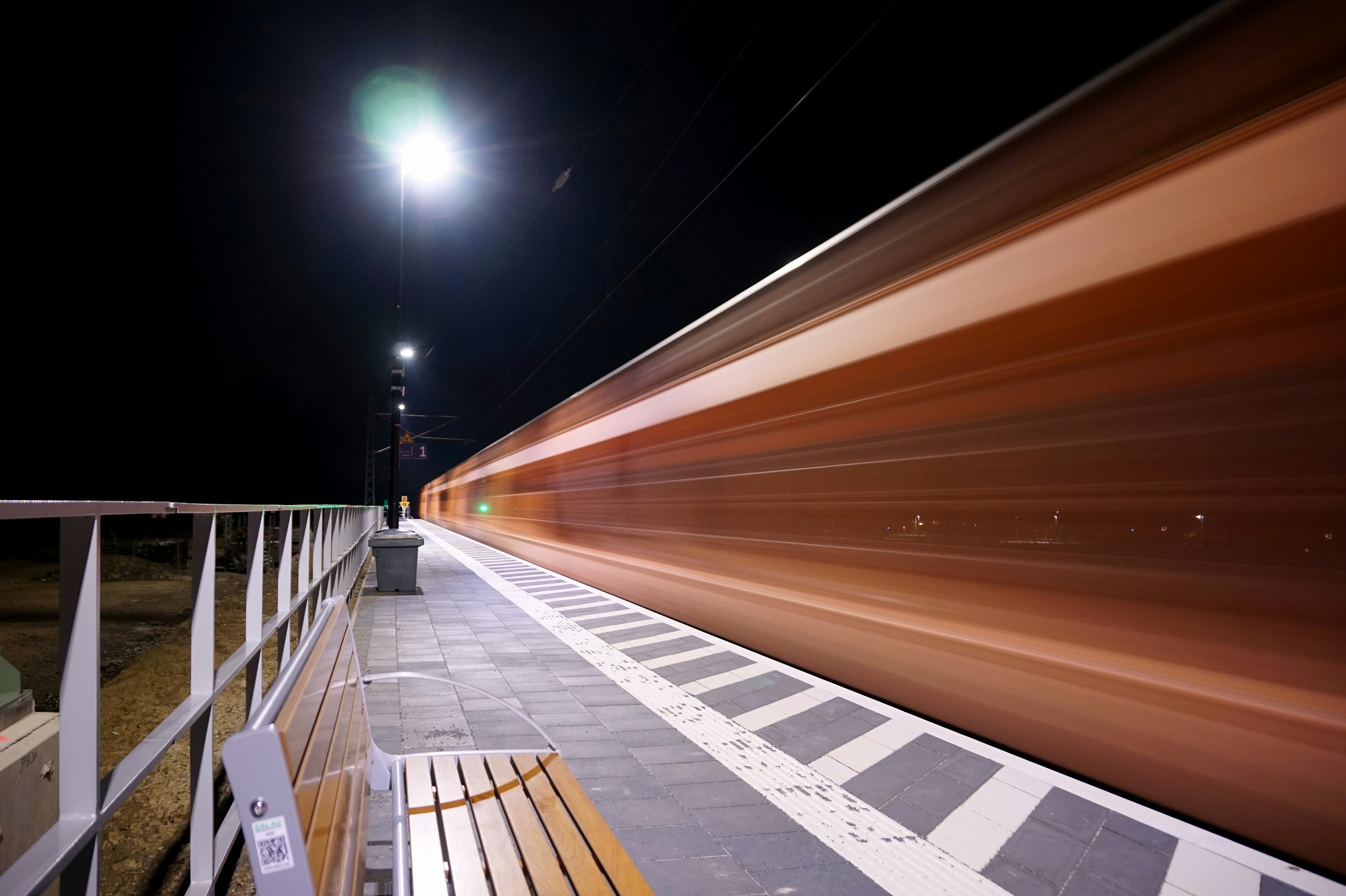Ein Zug rast nachts an einem Bahnsteig vorbei.