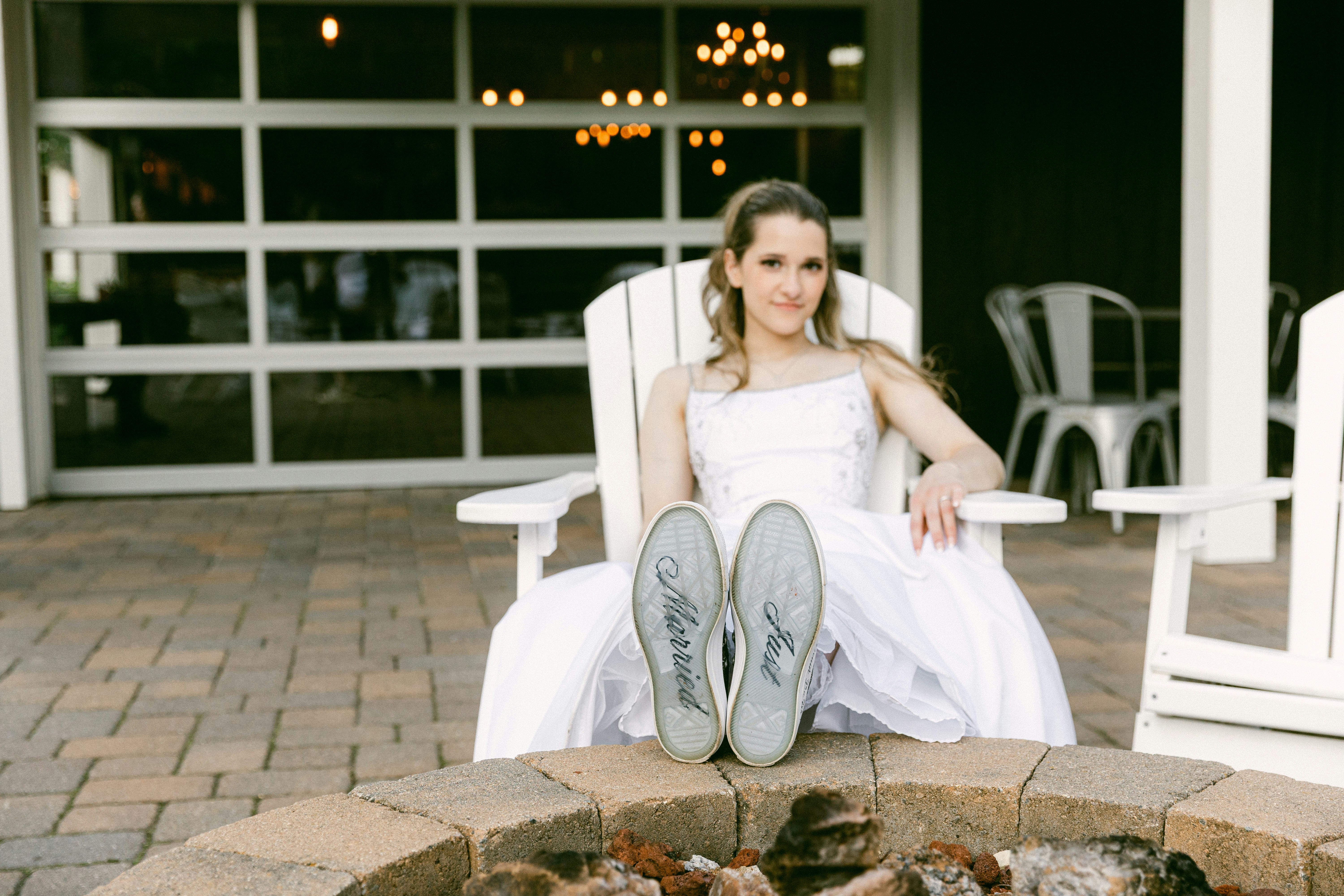 La mariée en robe de mariée assise sur des chaises Adirondack