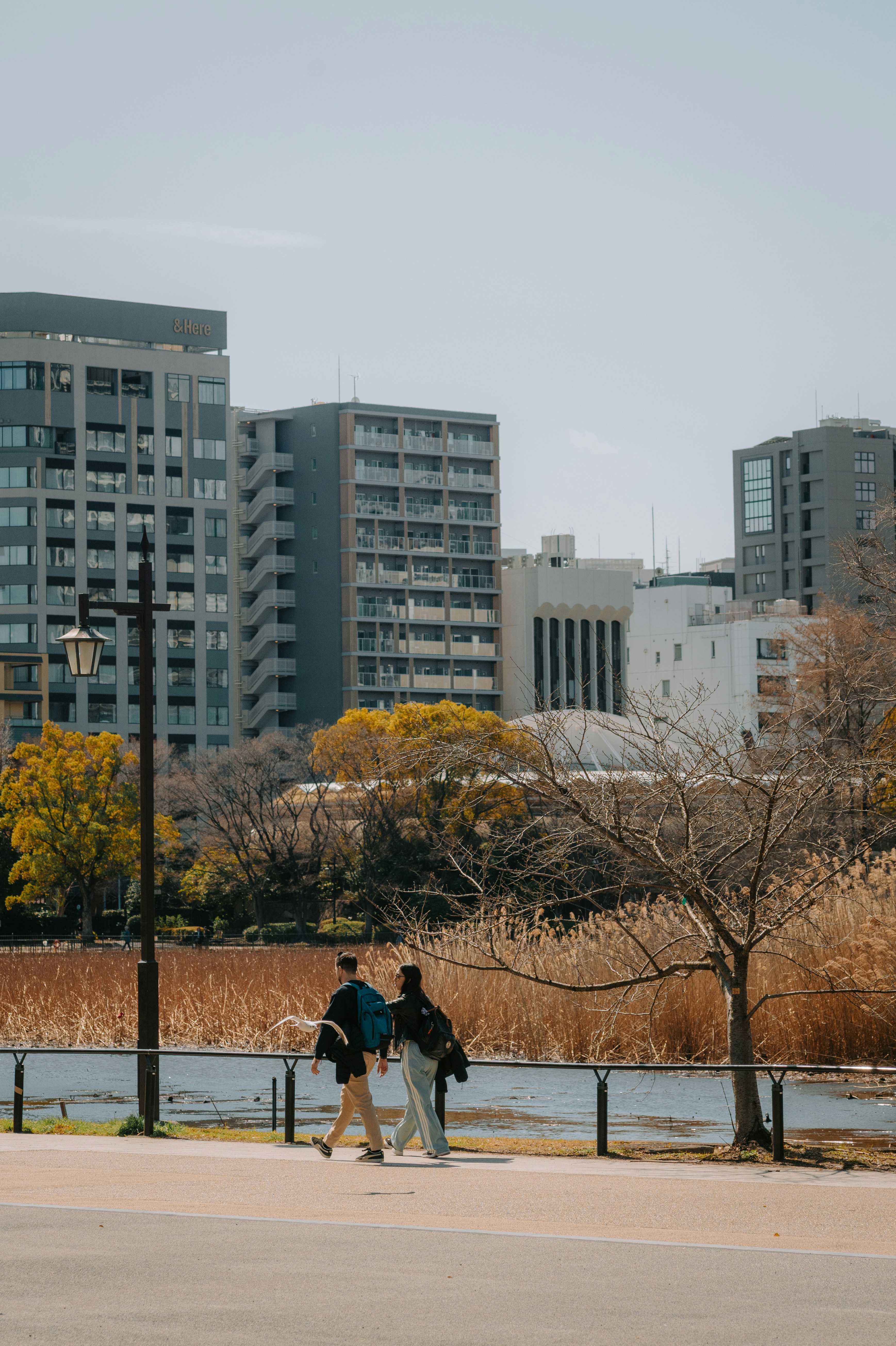 Two people walk along a path with buildings in background