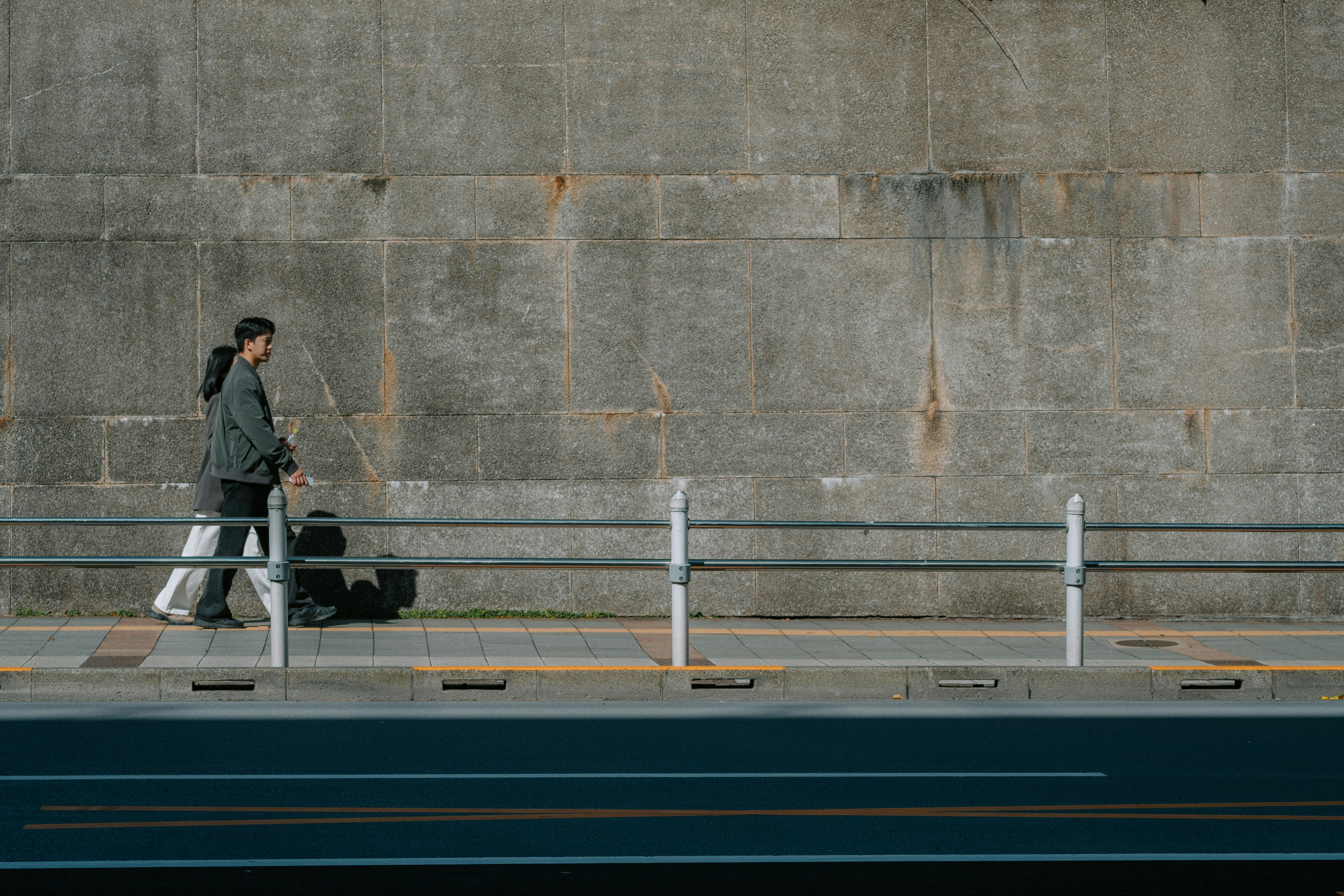 Man with luggage walking along a concrete wall