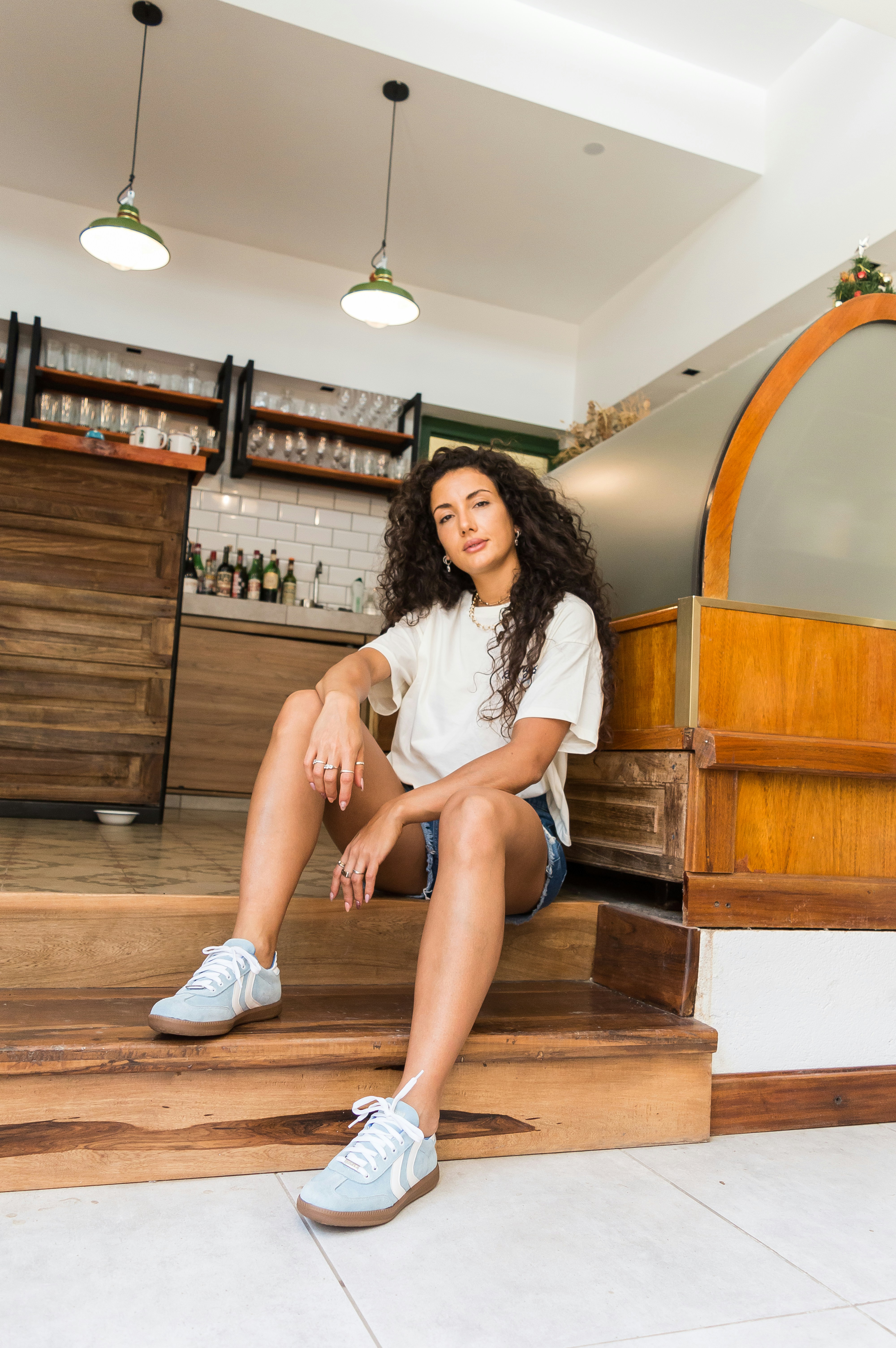 Young woman with curly hair sitting on wooden steps.