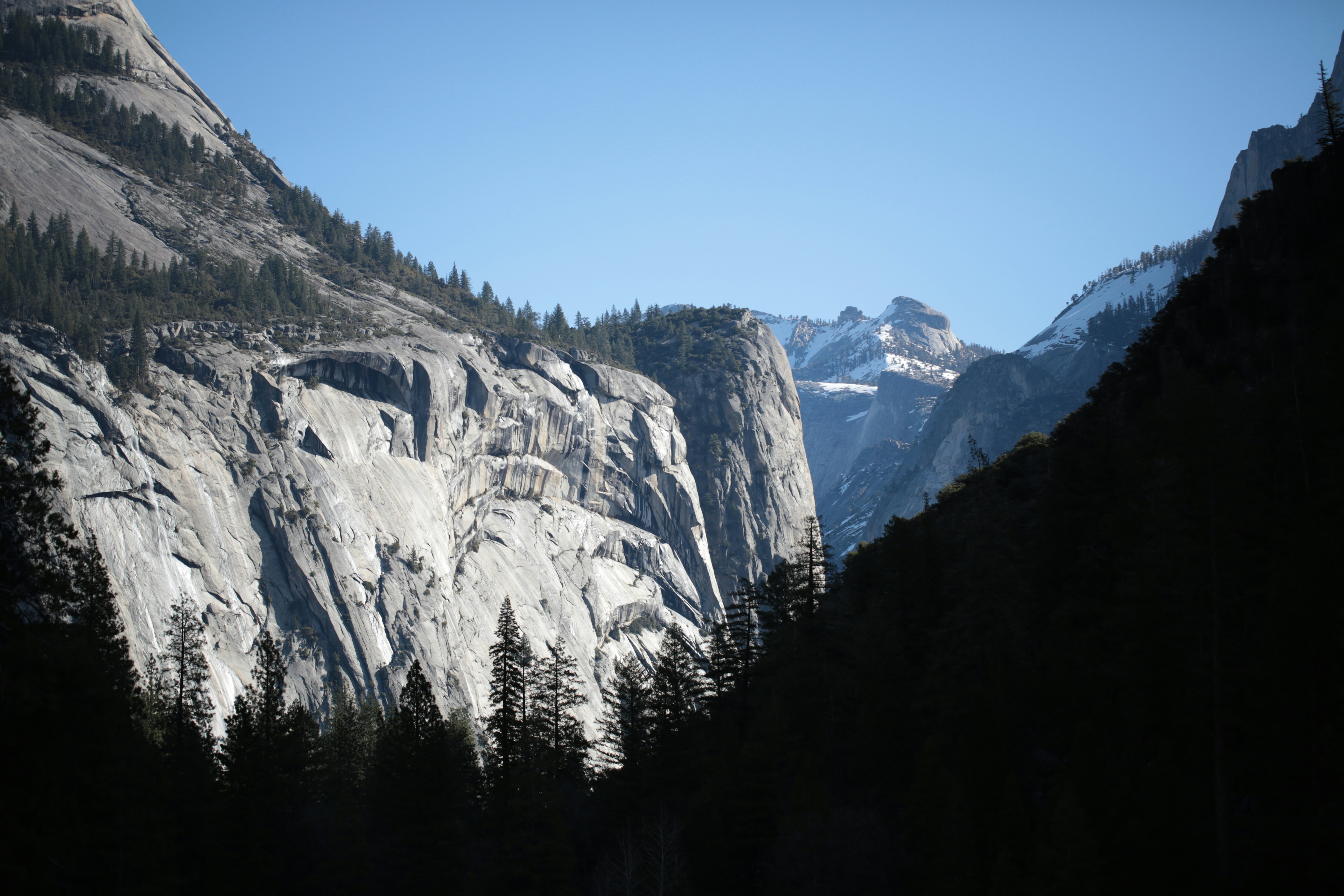 Majestic granite cliffs rise under a clear blue sky.