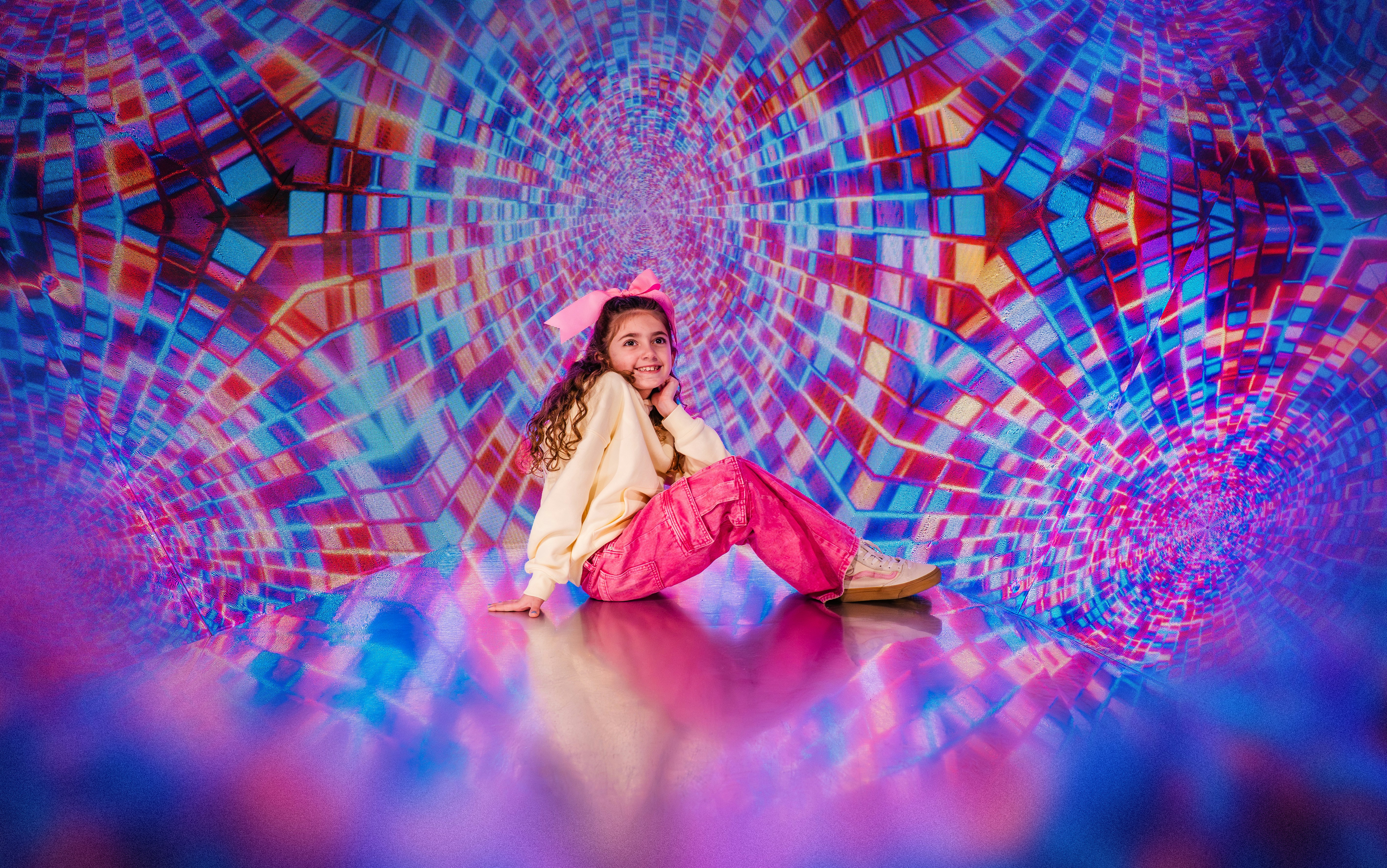 Garota sentada em frente a um fundo caleidoscópico colorido