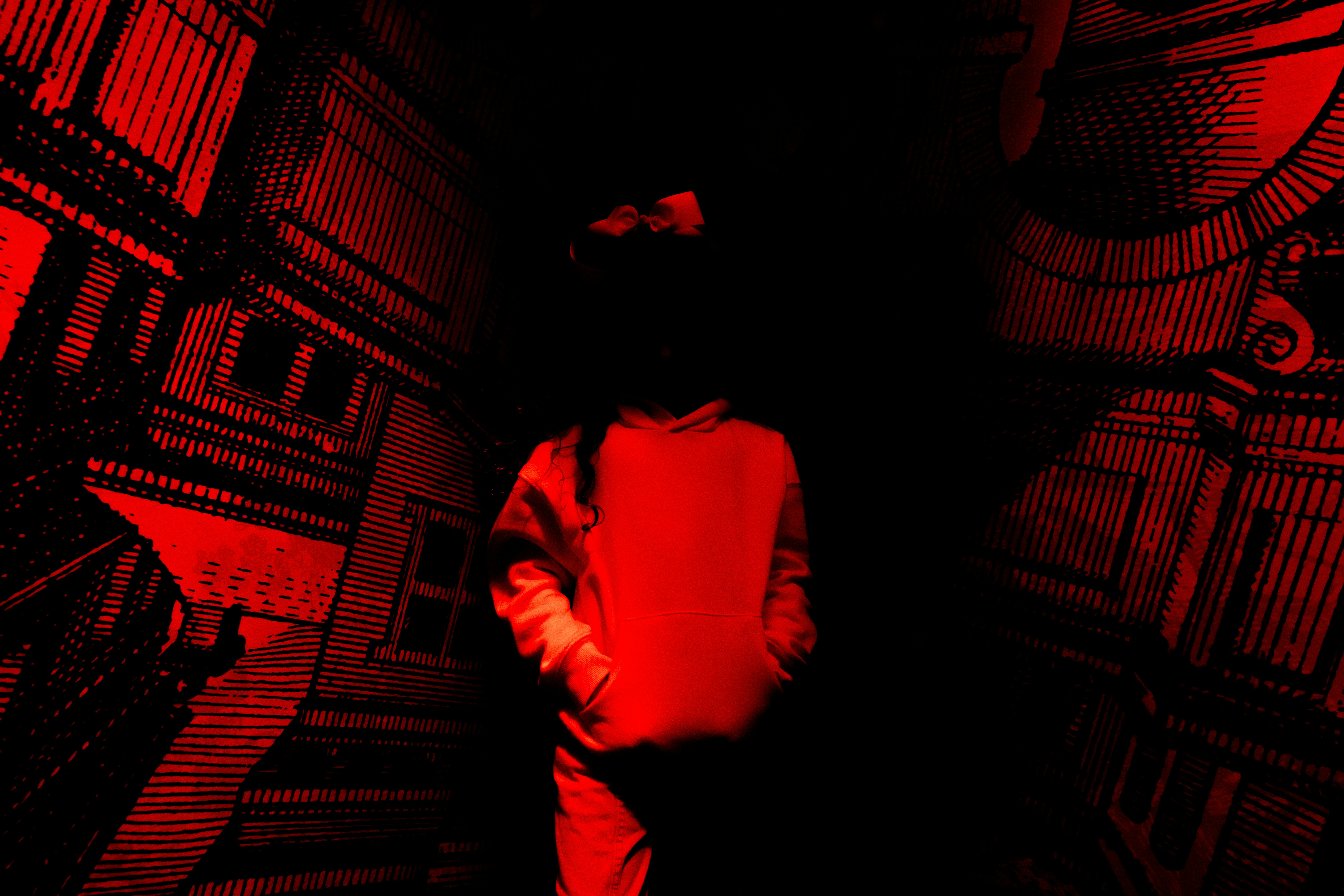 Uma pessoa está em um corredor escuro iluminado em vermelho.