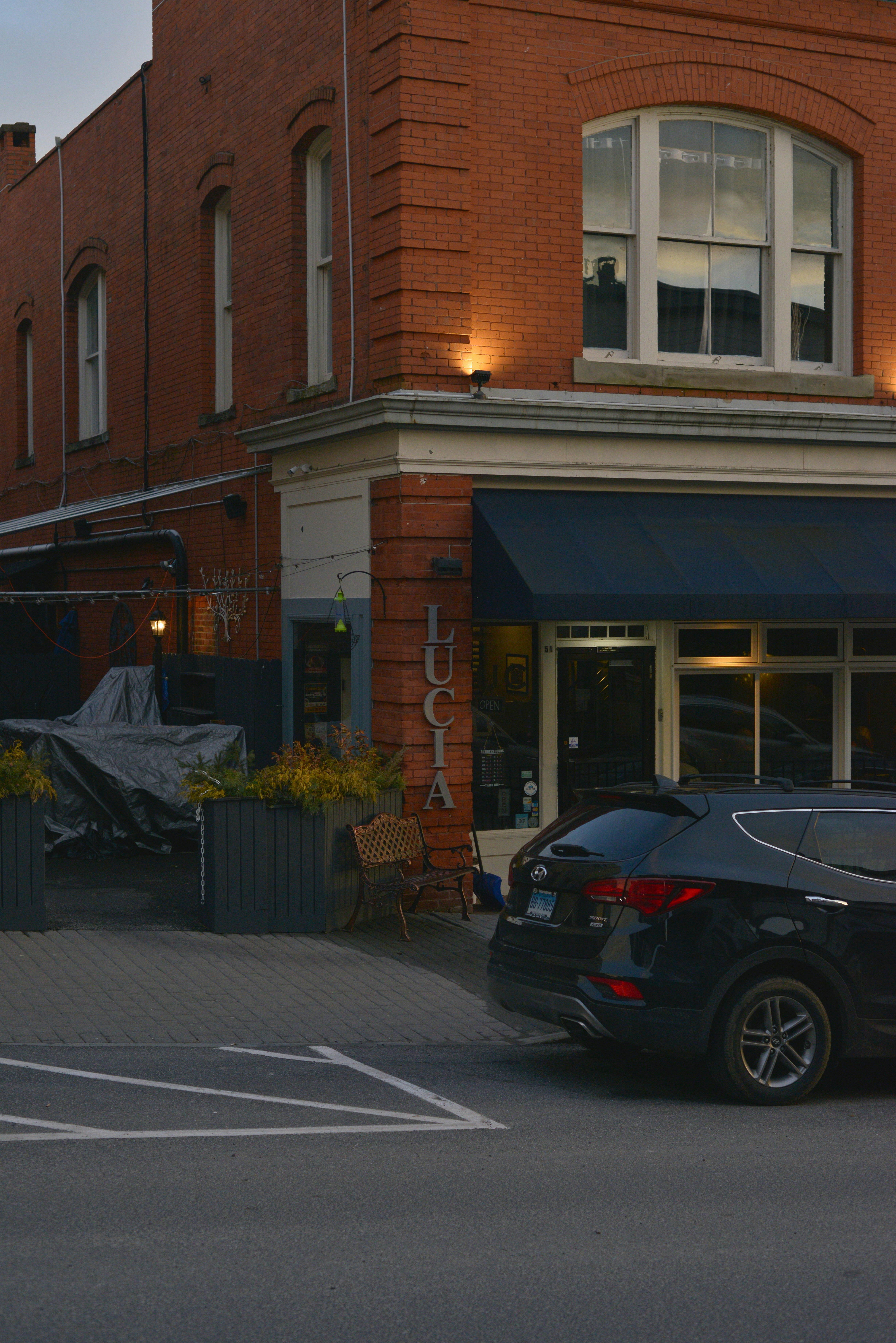 Schwarzer SUV vor einem Backsteingebäude mit Vordach geparkt.