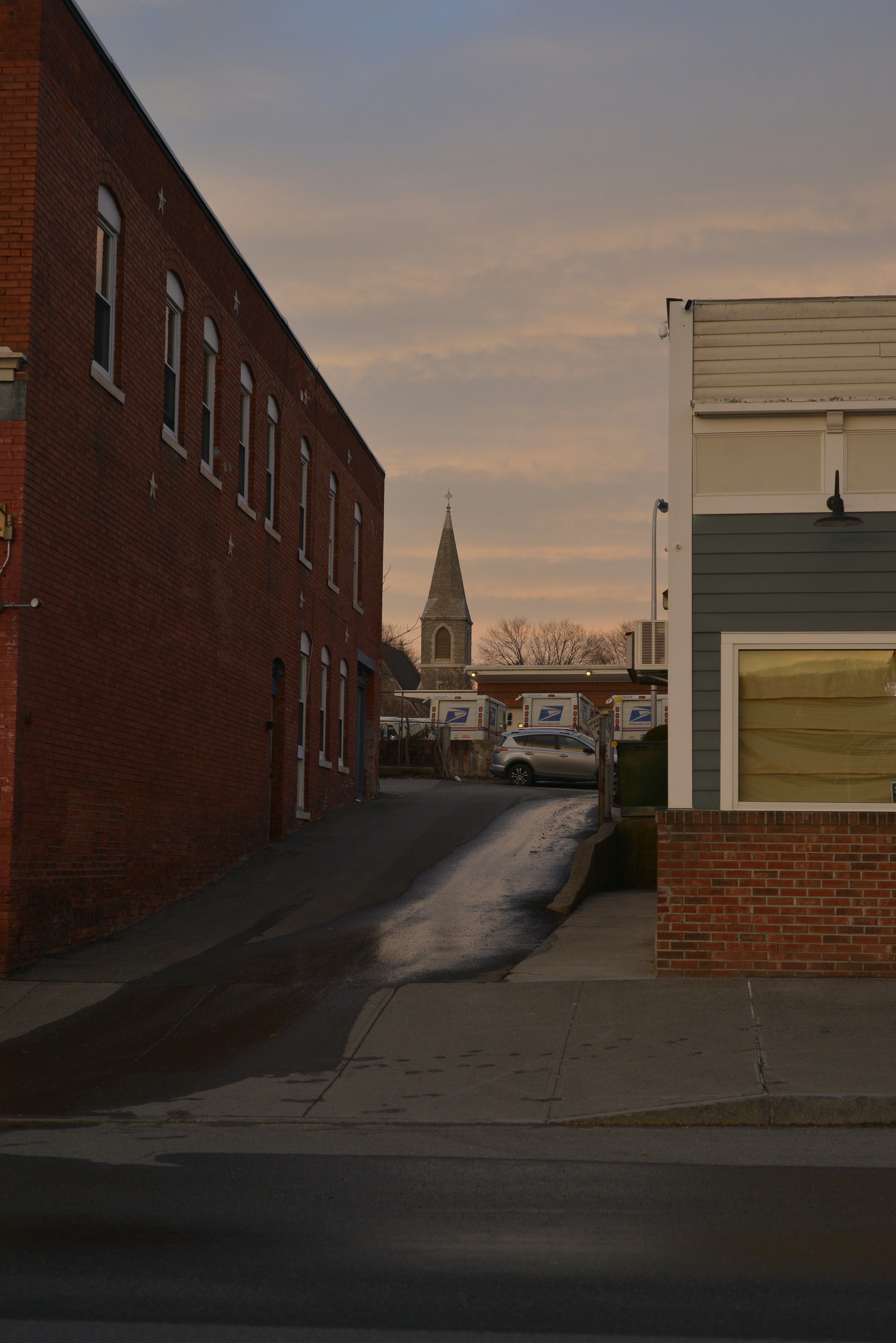 Eine steile Gasse führt bei Einbruch der Dämmerung zu einem Kirchturm.