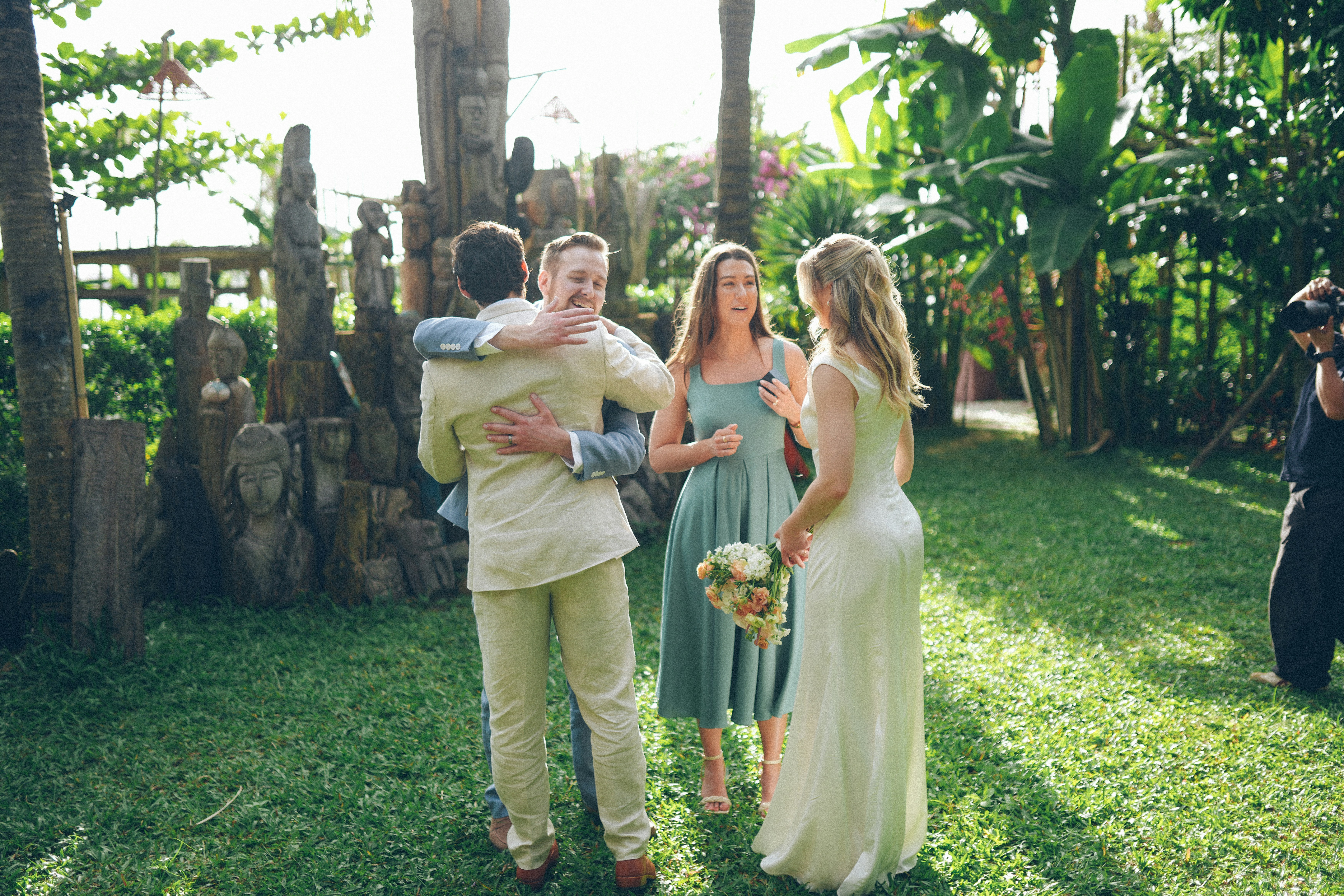 Couple hugging a guest at an outdoor wedding ceremony