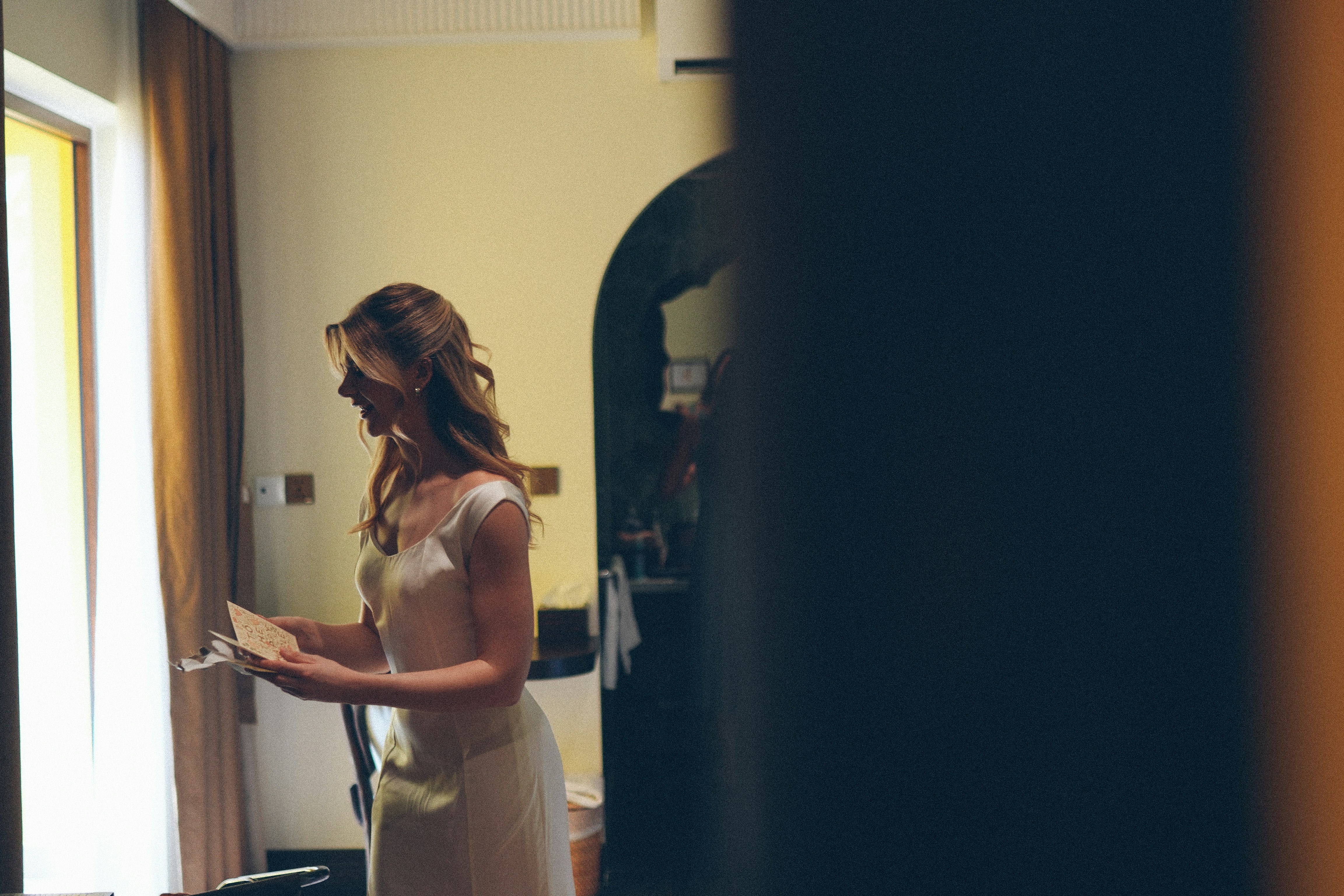 A bride in a white dress reads a letter.